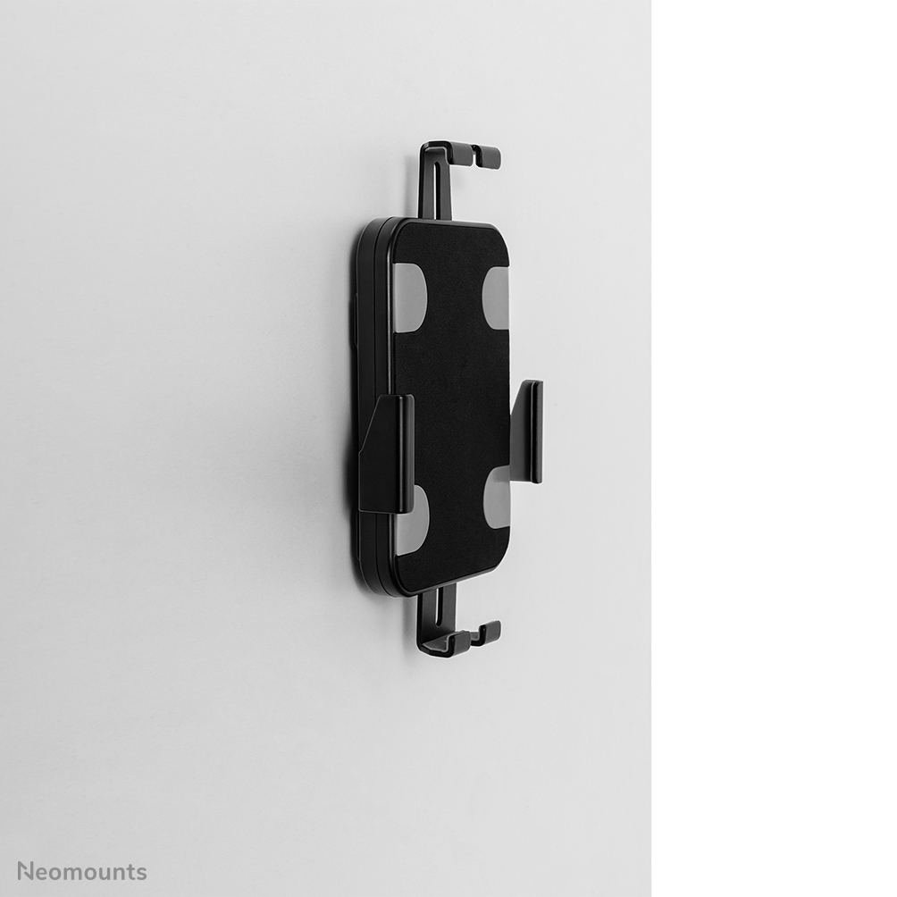 A black tablet holder mounted on a white wall. It has a rectangular shape with four gray padded areas and black hooks.