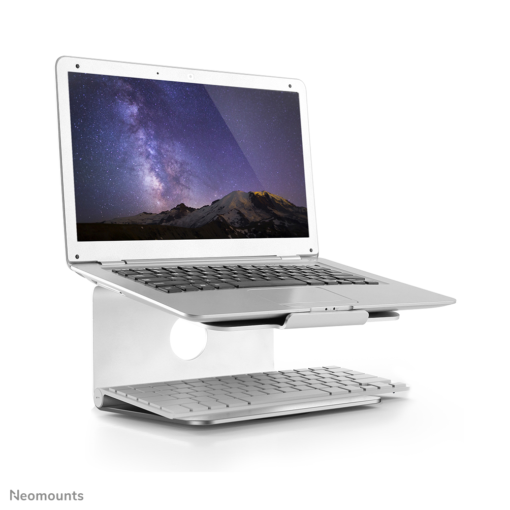 Silberner Laptop auf einem Ständer mit separater Tastatur. Der Bildschirm zeigt eine Sternennacht und einen Berg.
