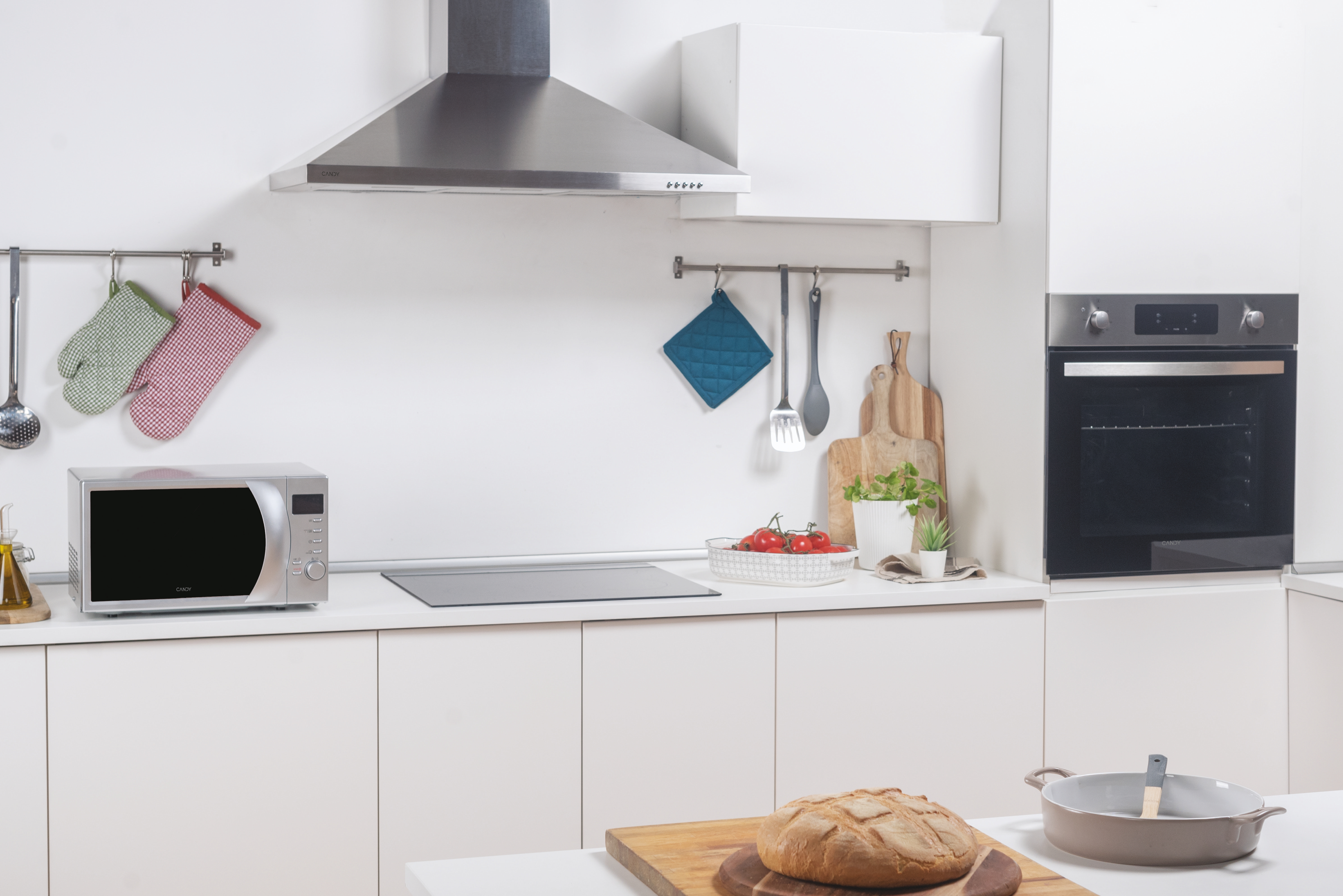 Cucina con microonde, forno e utensili da cucina. Una pagnotta è su un tagliere in primo piano.