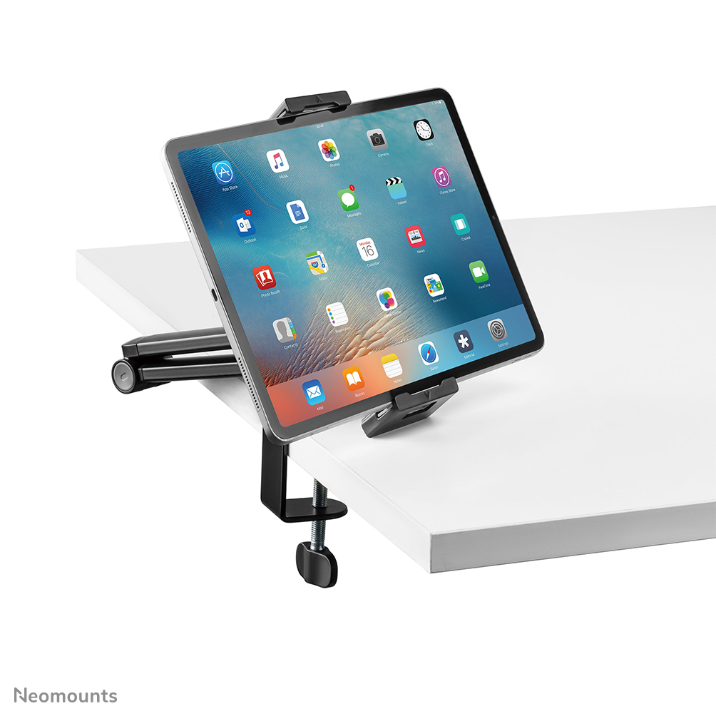 Une tablette iPad est maintenue par une pince noire fixée à une table blanche. L'écran de l'iPad affiche des icônes d'applications.
