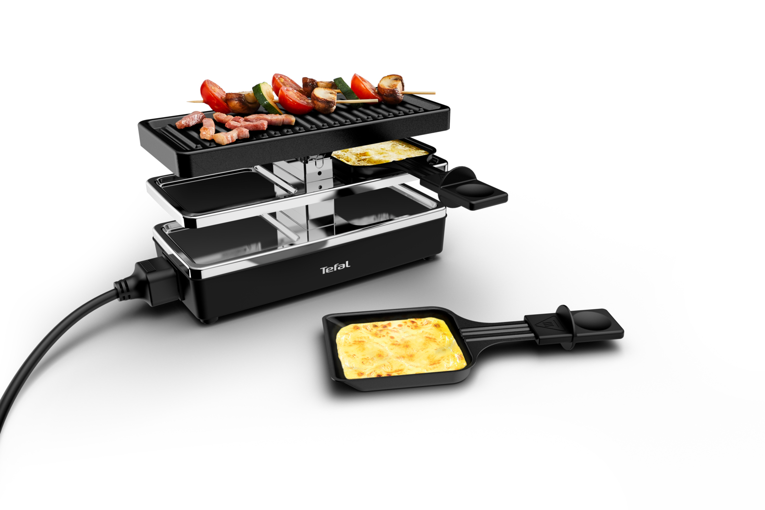 Grill do raclette Tefal z szaszłykami z warzyw i mięsa. Ser topi się na patelni. Czarny i srebrny design, białe tło.