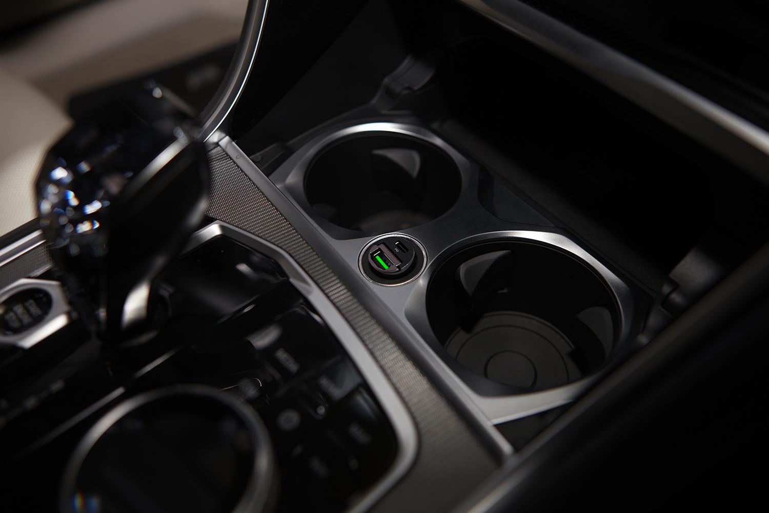 Detail des Autoinnenraums. Becherhalter mit USB-Anschluss. Schalthebel und Konsole sind sichtbar. Die Farben sind Schwarz und Silber.
