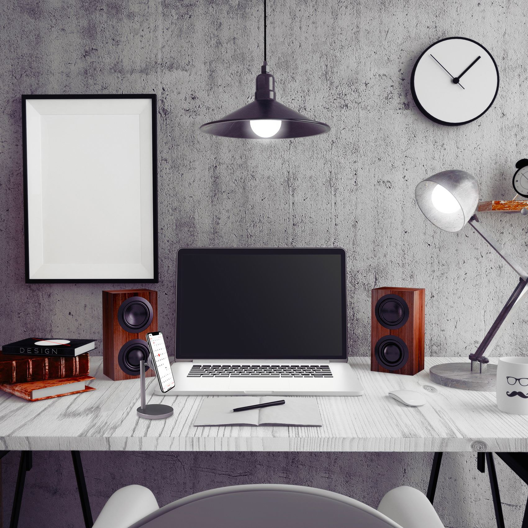 Ein Schreibtisch mit Laptop, Lautsprechern, Telefon, Büchern und Lampe. Eine Uhr und ein Bilderrahmen an der Wand.