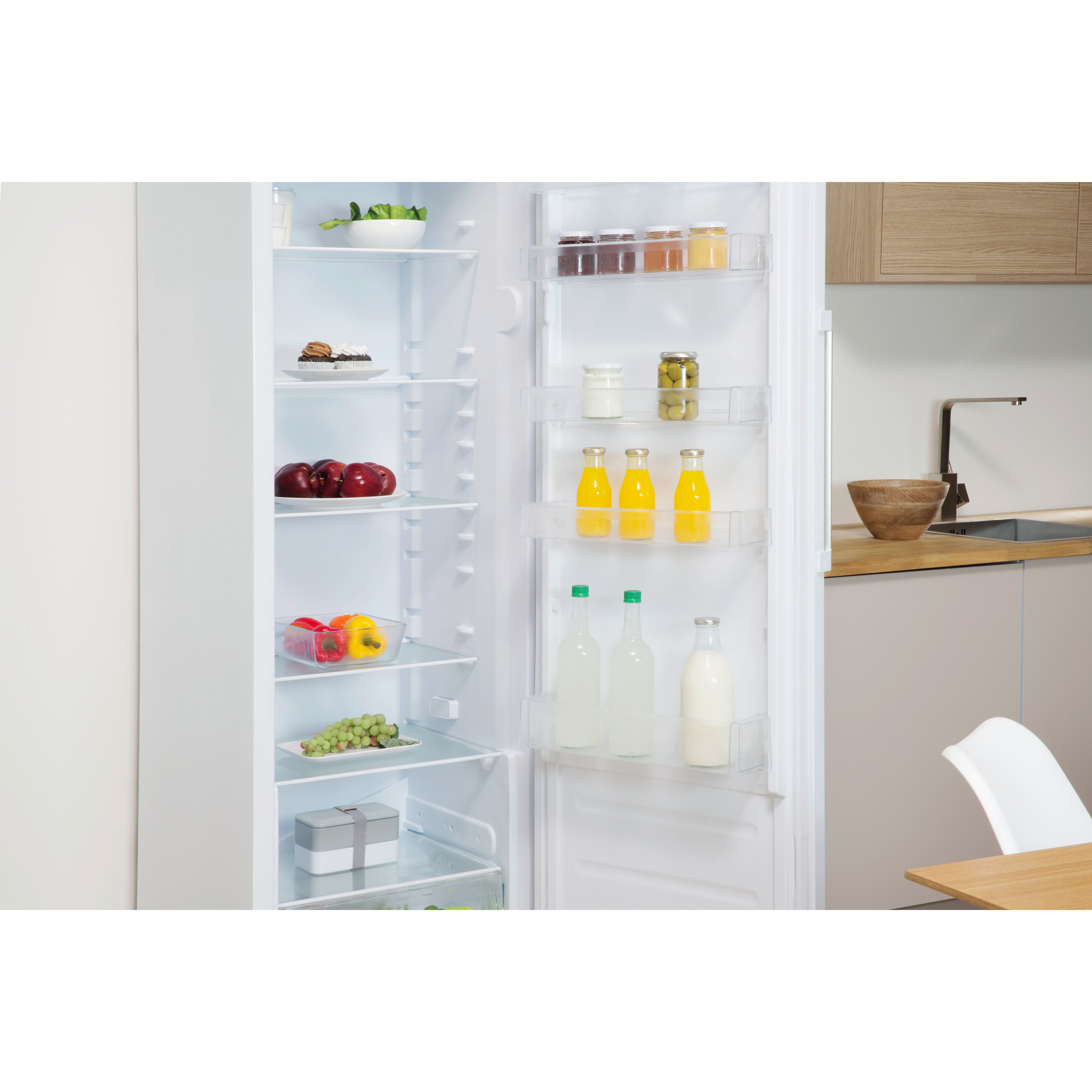 Refrigerador abierto lleno de comida: frascos, botellas, manzanas, pimientos, uvas. Fondo de cocina.