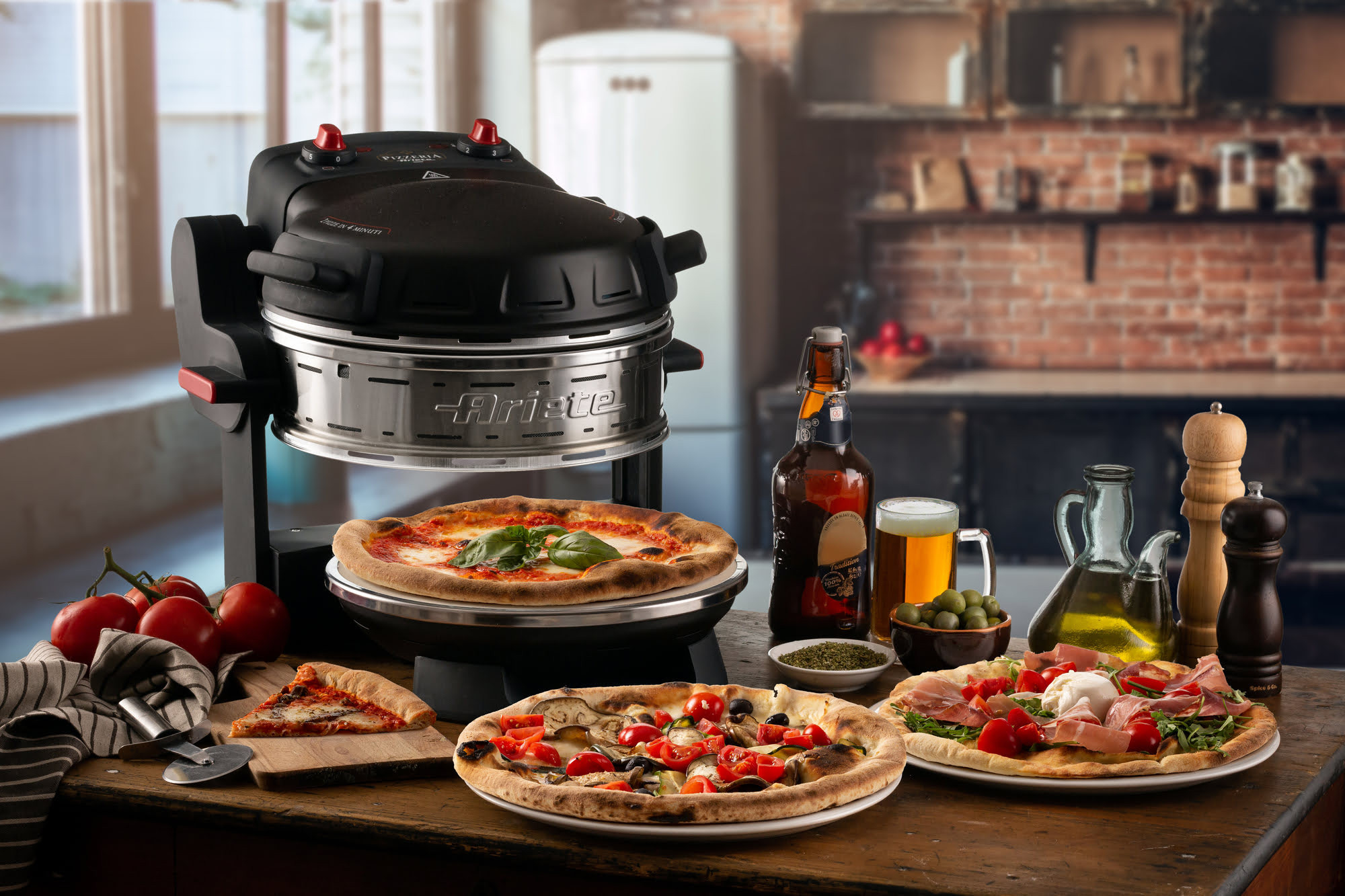 Pizza-oven met pizza's, tomaten, bier en olijfolie op een houten tafel. Een keuken op de achtergrond.