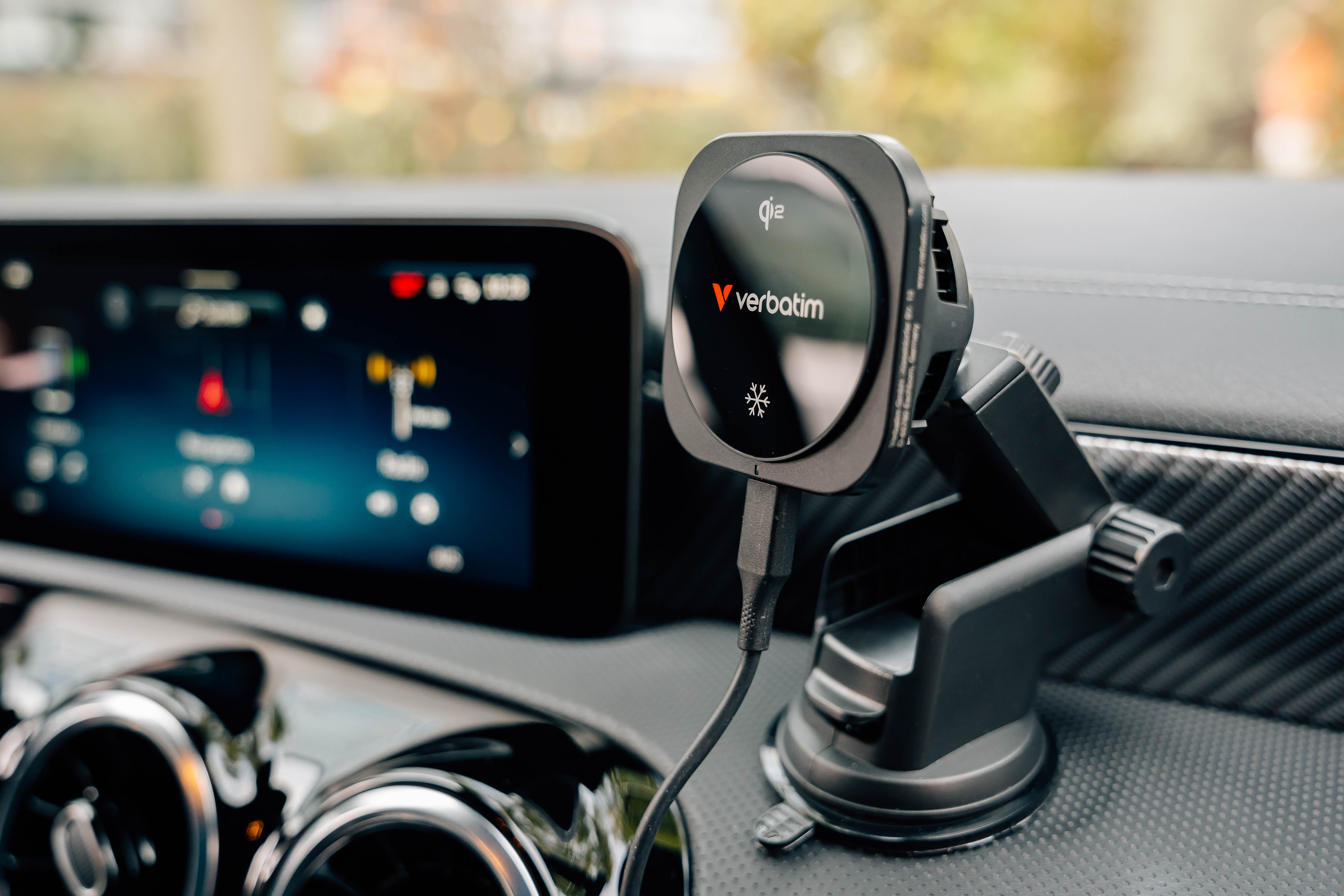 Schwarzes drahtloses Verbatim-Ladegerät im Auto. Bildschirm im Hintergrund. Kabel am Ladegerät angeschlossen.