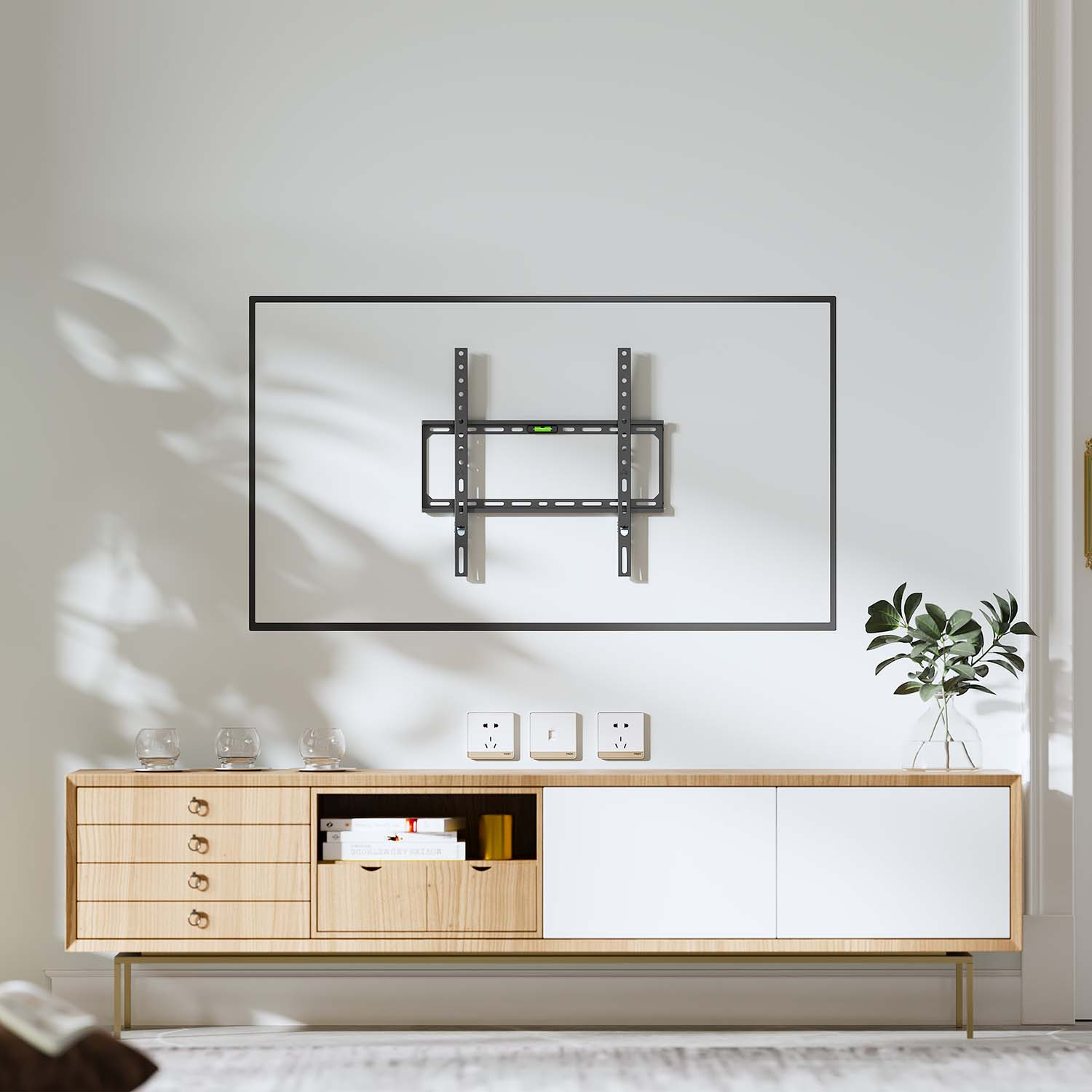 Un supporto a parete per TV è su un muro bianco. Sotto c'è un mobile in legno con bicchieri di vetro e una pianta in un vaso.
