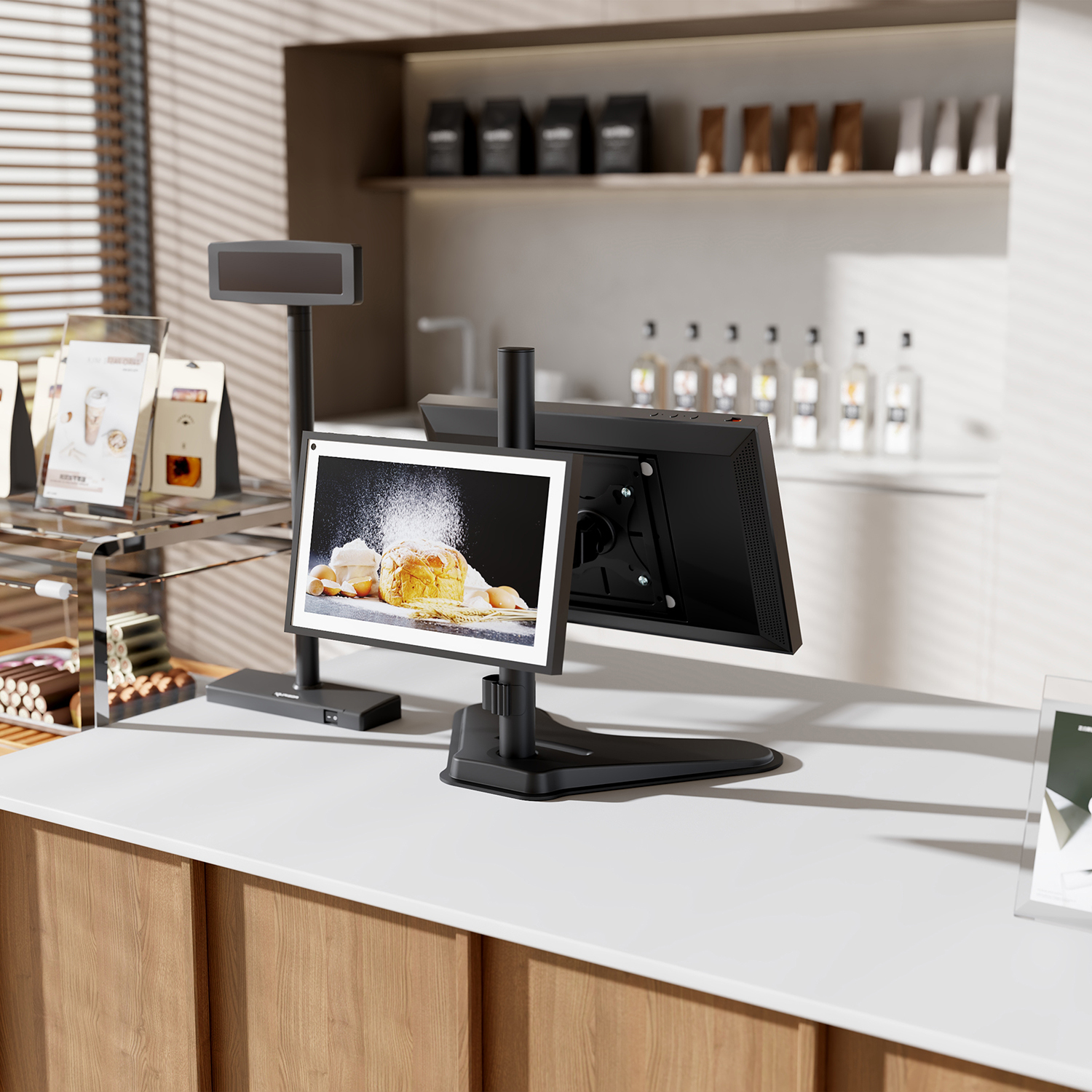 Bancone di un moderno caffè con schermo di computer che mostra pane. Espositori, schermo e vari prodotti sono visibili.