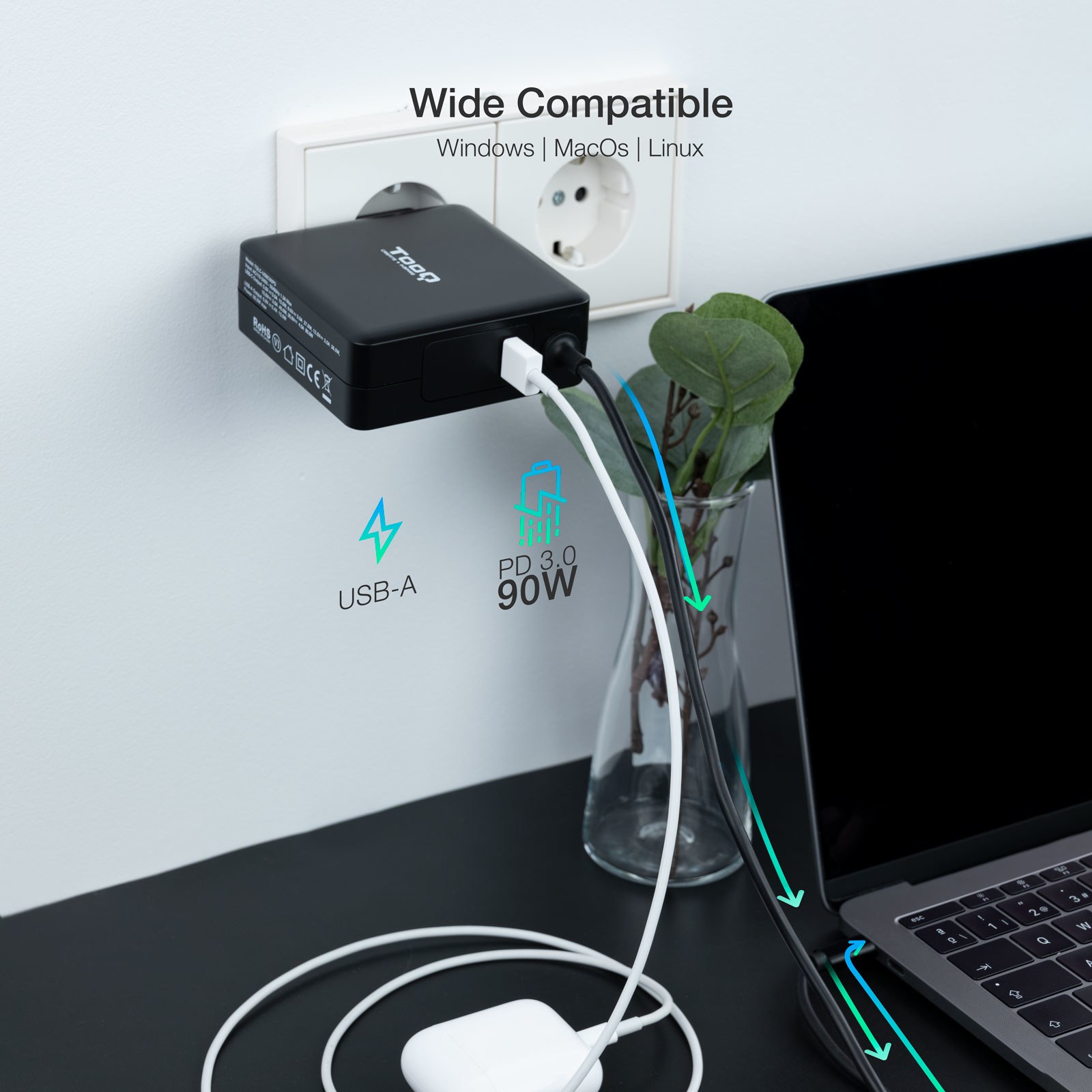 Un adaptador de corriente negro está enchufado a una pared. Los cables se conectan a una computadora portátil. El texto dice Wide Compatible.