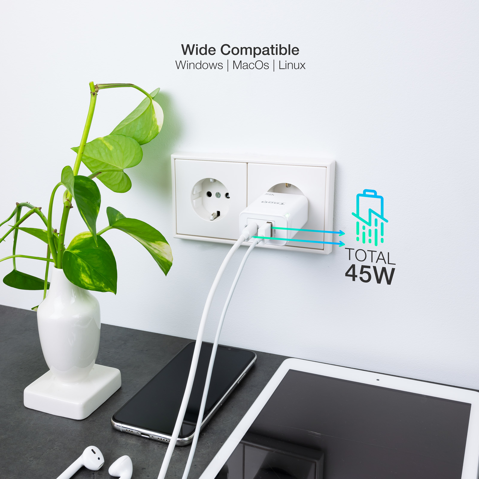 Cargador blanco enchufado, cargando teléfono y tableta. Planta en jarrón a la izquierda. Texto 45W a la derecha.