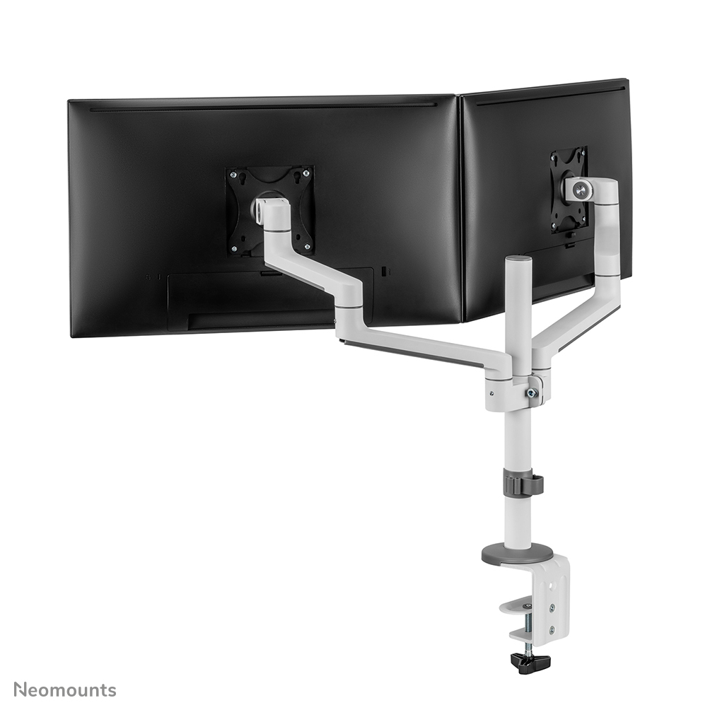 A white dual monitor arm with two black monitors. The arm is attached to a desk clamp. The brand name 'Neomounts' is at the bottom.