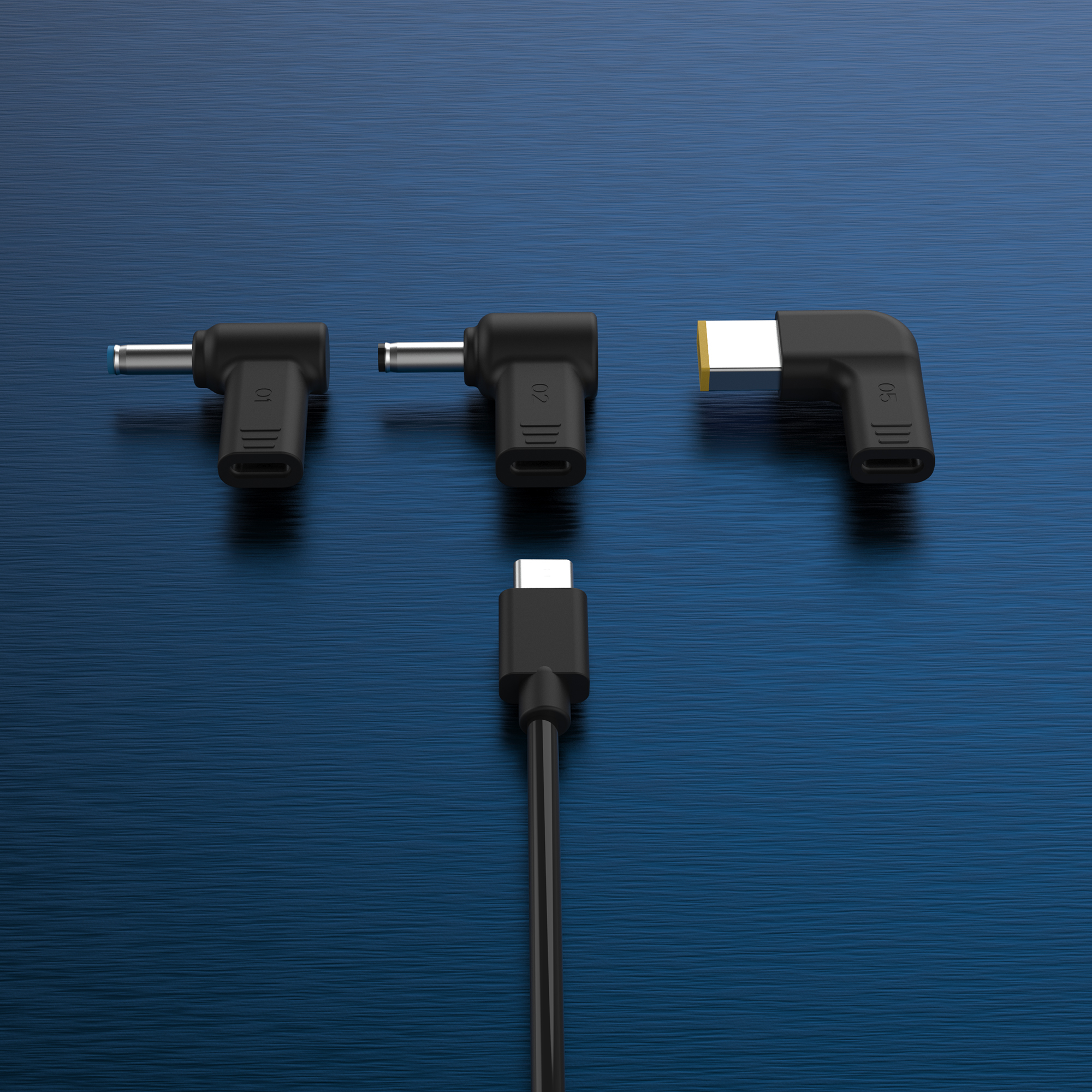 Tres adaptadores de corriente negros para portátiles con diferentes puntas y un cable USB-C sobre superficie azul.