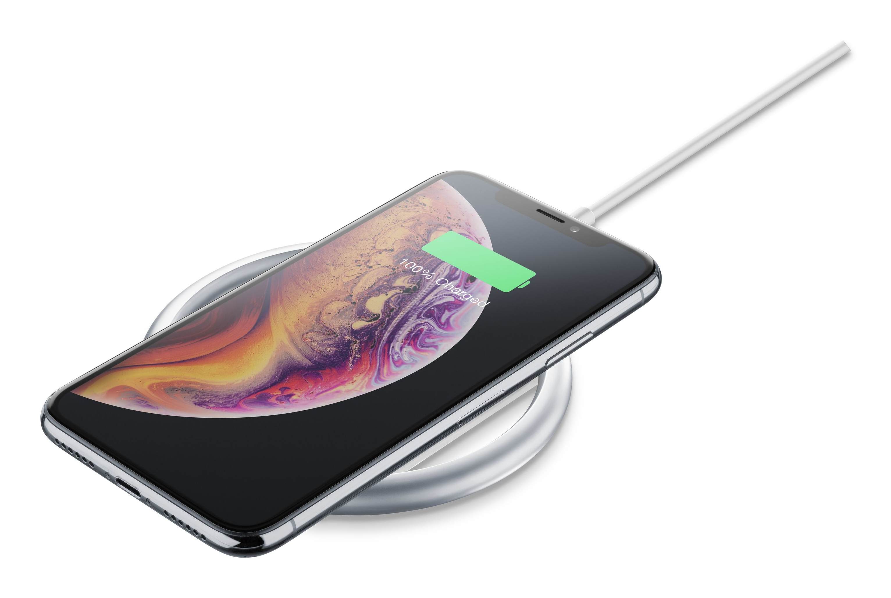 iPhone en un cargador inalámbrico, cargando. La pantalla muestra 100% cargado. Fondo blanco.