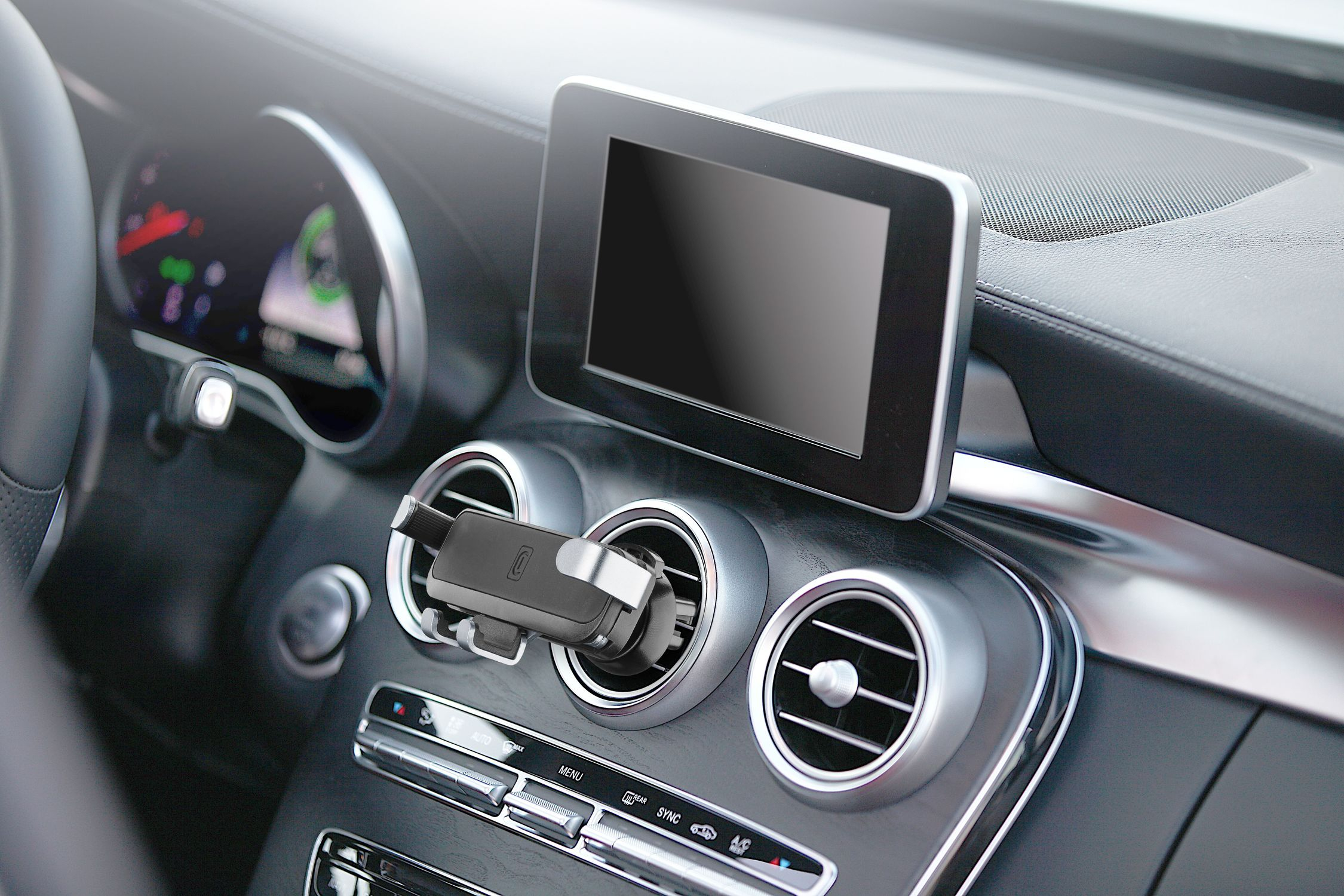 Interior del coche con soporte para teléfono, pantalla y detalles del salpicadero. También se ven las rejillas de ventilación y los controles.