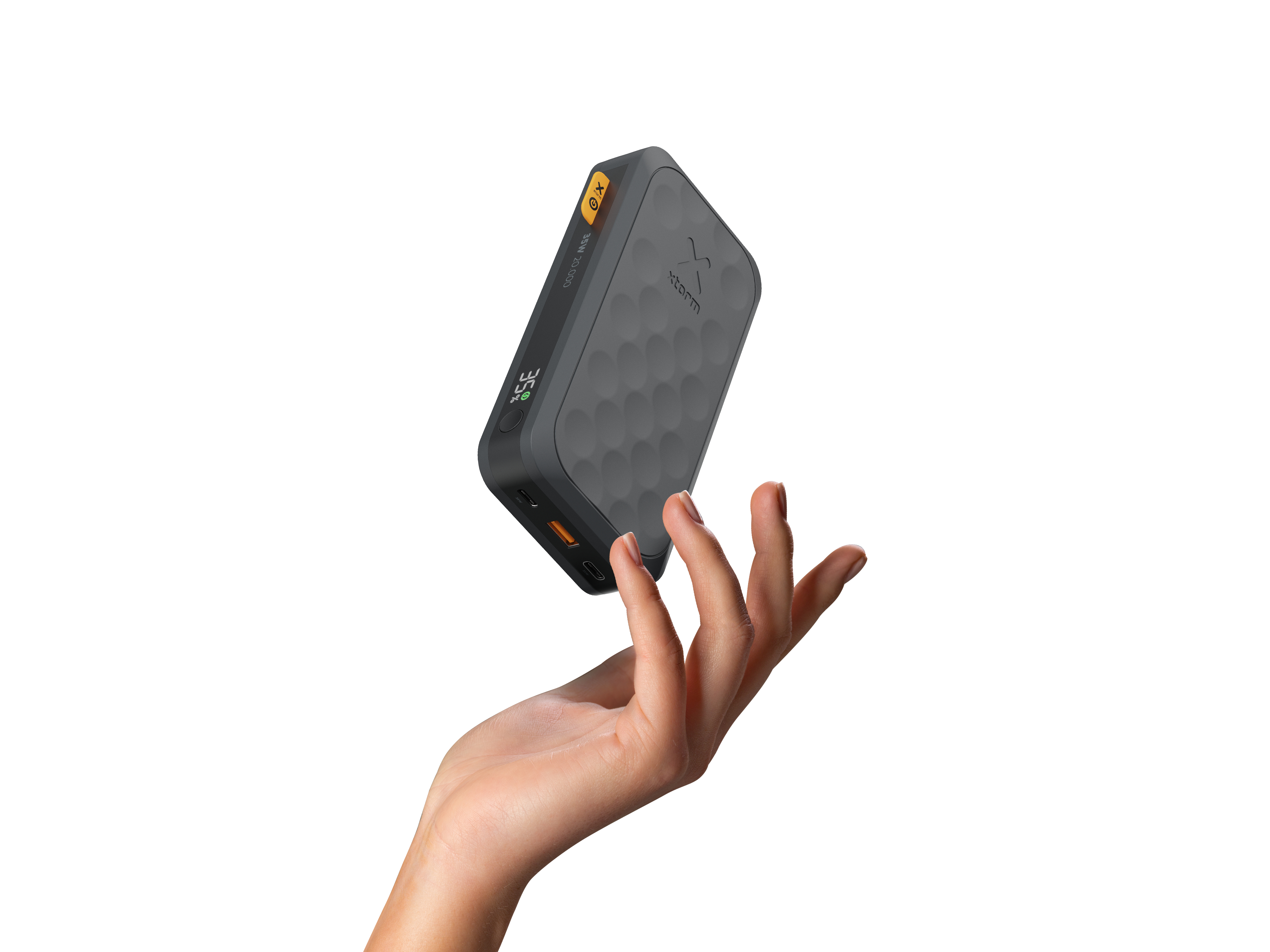 Une main tient une batterie externe grise. La batterie externe a un écran indiquant 35 % de charge et un bouton jaune.