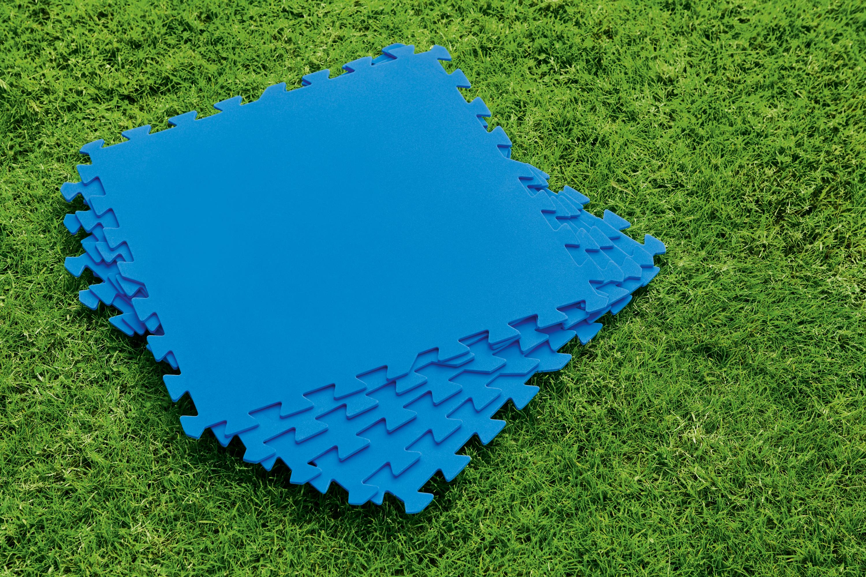 Alfombras de espuma azul entrelazadas apiladas sobre hierba verde. Las alfombras son como rompecabezas.