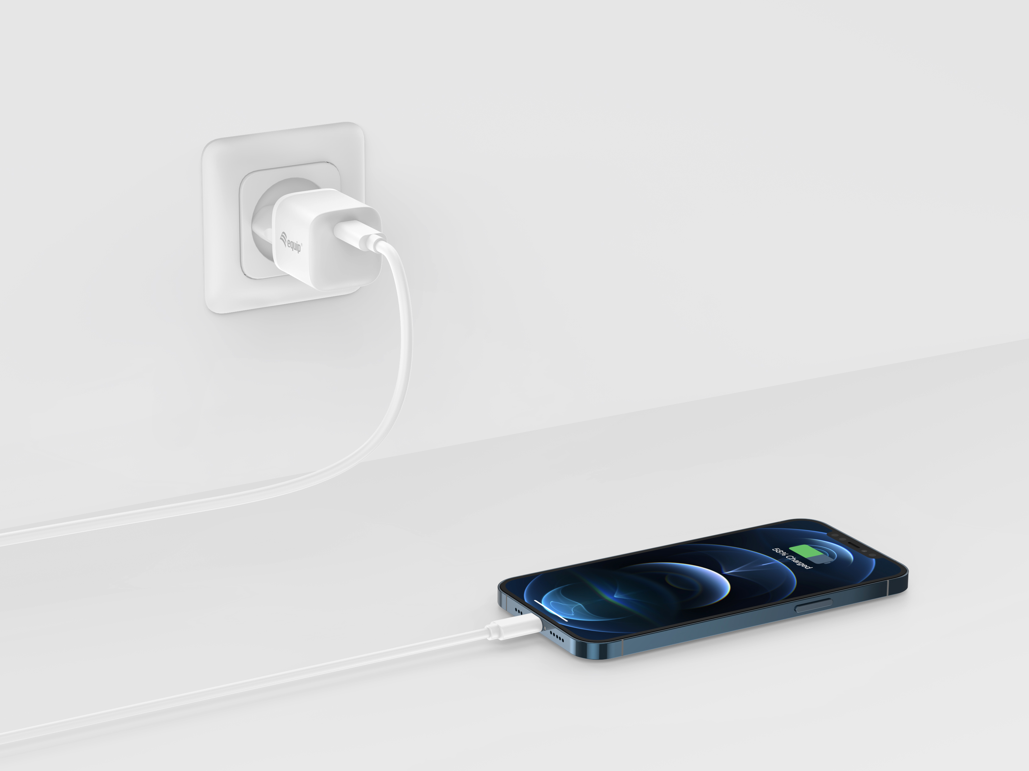 Un cargador de teléfono blanco está enchufado a la pared y conectado a un iPhone azul que muestra el estado de carga.