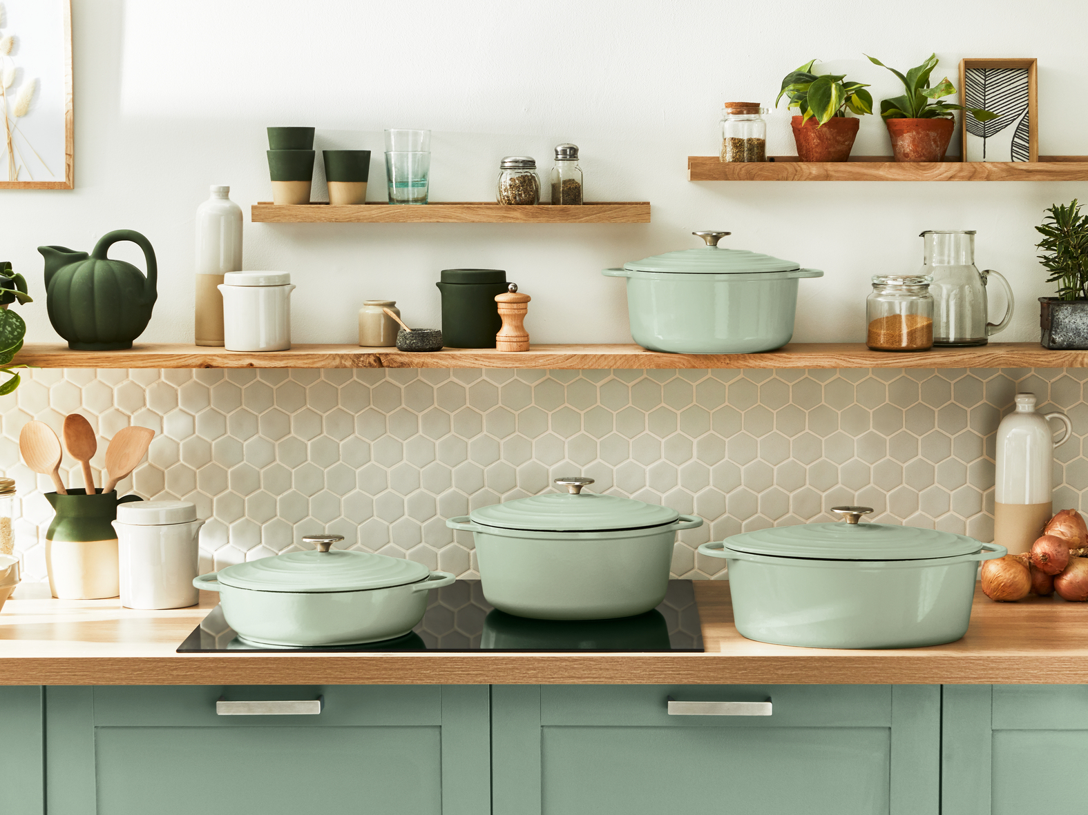 Scena kuchenna z półkami. Zielone garnki i przybory na blacie. Rośliny i przyprawy na półkach.