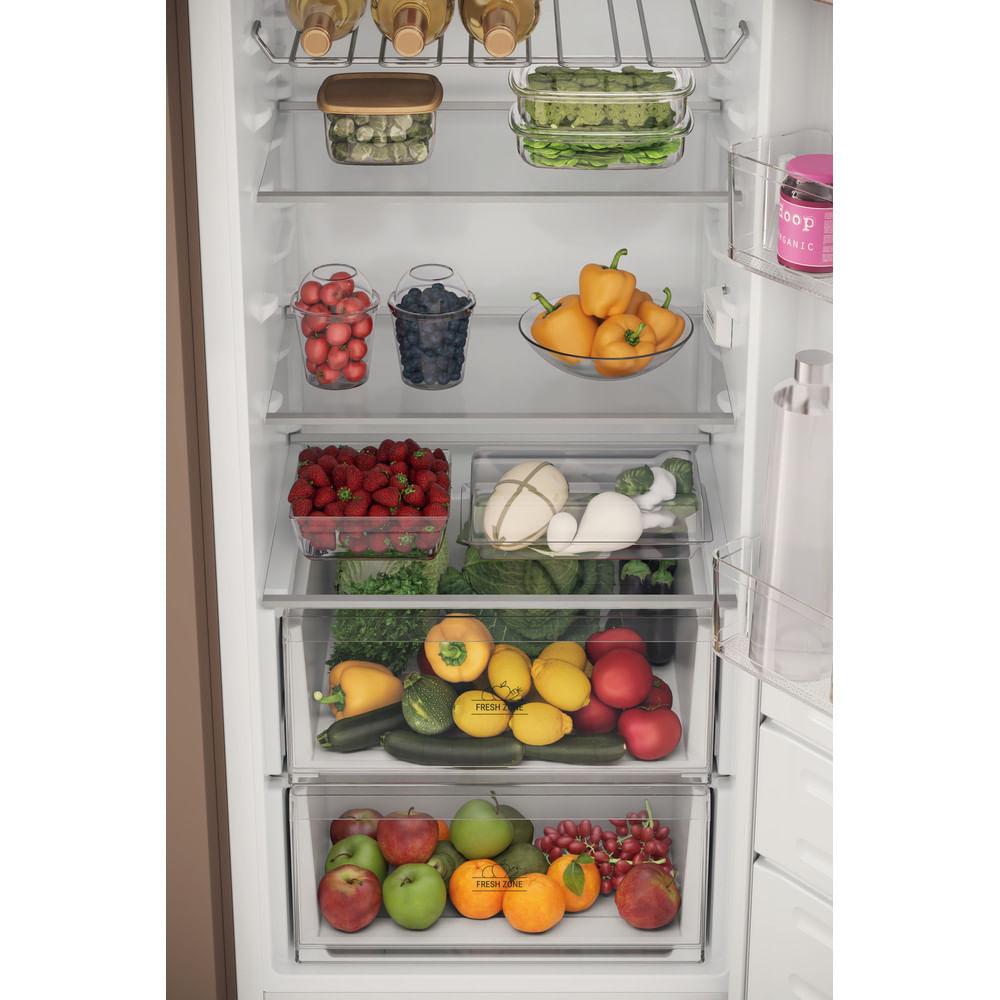 Interno di un frigorifero pieno di frutta e verdura. Fragole, peperoni, pomodori e altri articoli sono visibili.