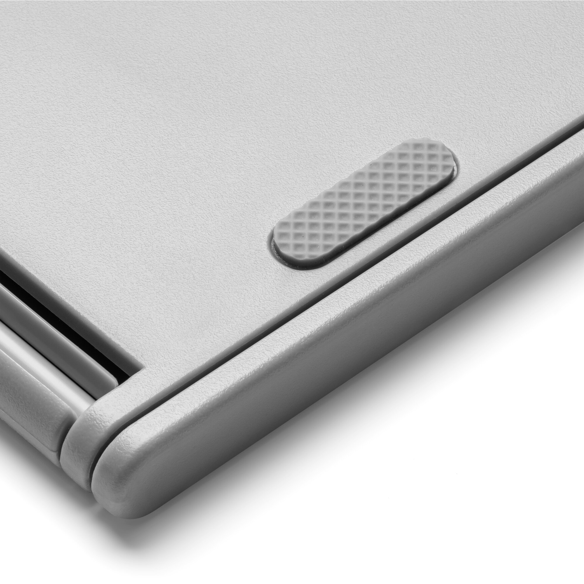 Close-up of a gray plastic surface with a textured button. The surface is angled. White background.