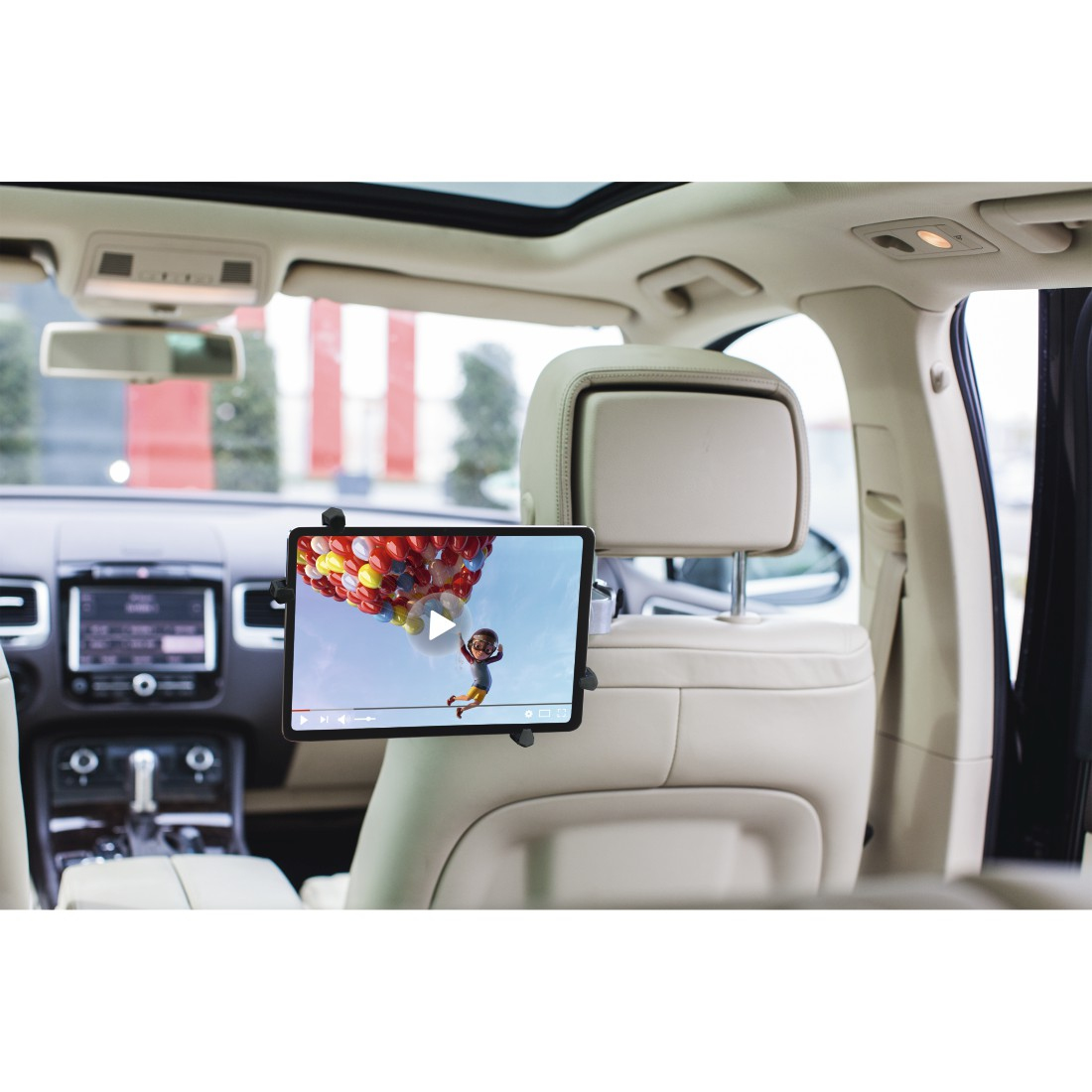 Tablet zamontowany na siedzeniu samochodu. Ekran pokazuje postać z kreskówki unoszącą się z balonami. Wnętrze samochodu widoczne.