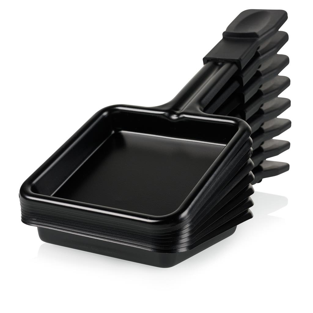 Stos czarnych patelni do raclette, każda z uchwytem. Są na białej powierzchni i są odizolowane. Patelnie są puste i czyste.