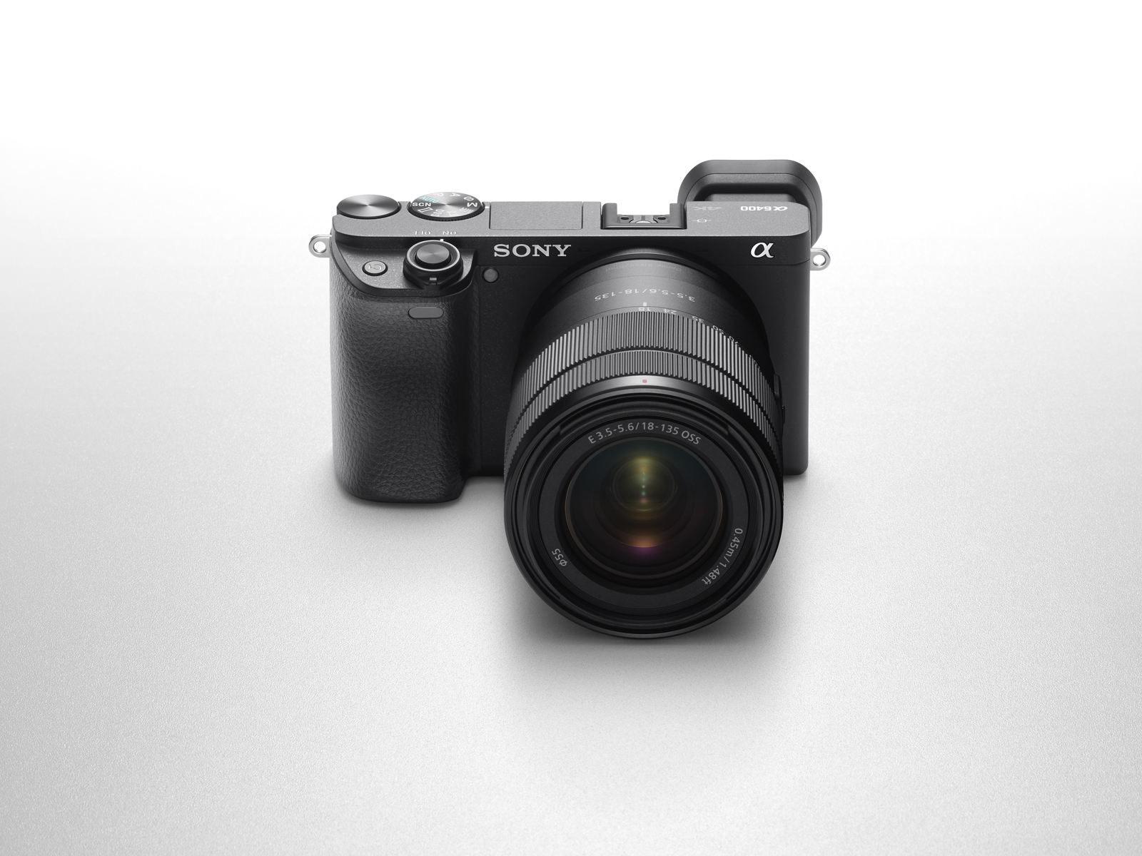 Una cámara Sony negra con lente centrada. La lente tiene marcas y la cámara está sobre una superficie gris claro.
