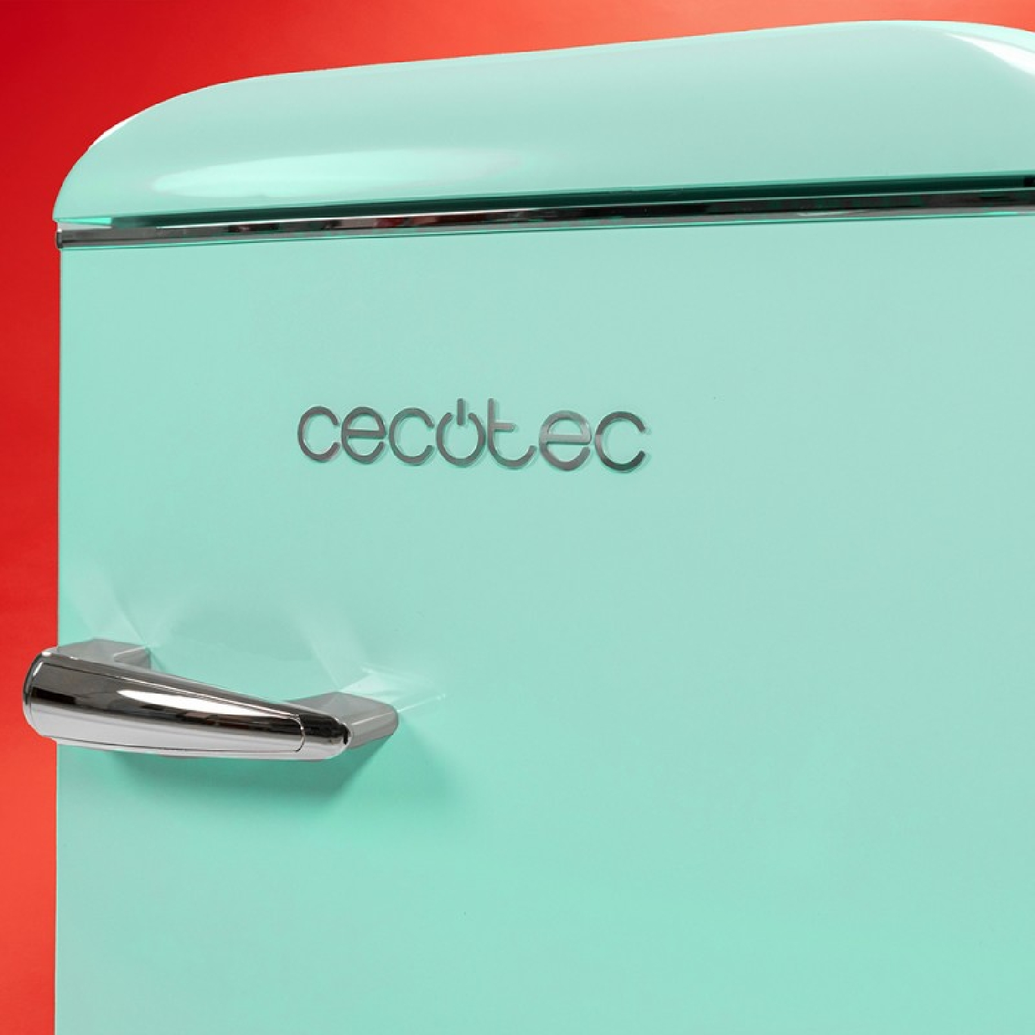 Miętowa zielona lodówka z chromowaną rączką i logo 'cecotec'. Tło jest czerwone.