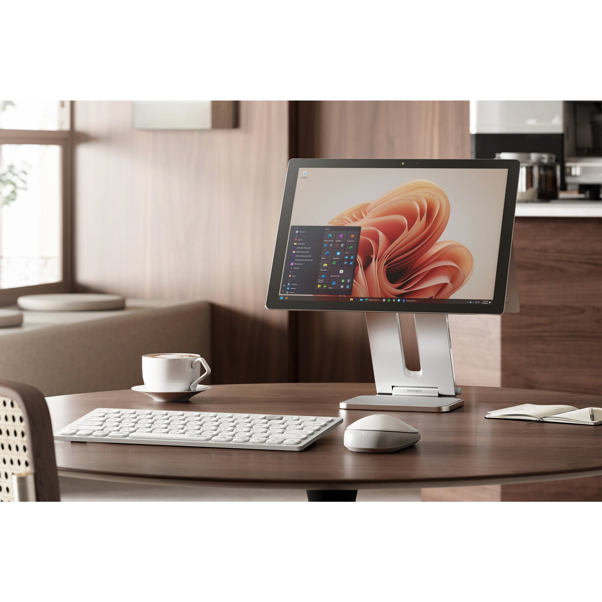 Une configuration informatique sur une table en bois, avec moniteur, clavier, souris et tasse à café. Arrière-plan chaleureux.