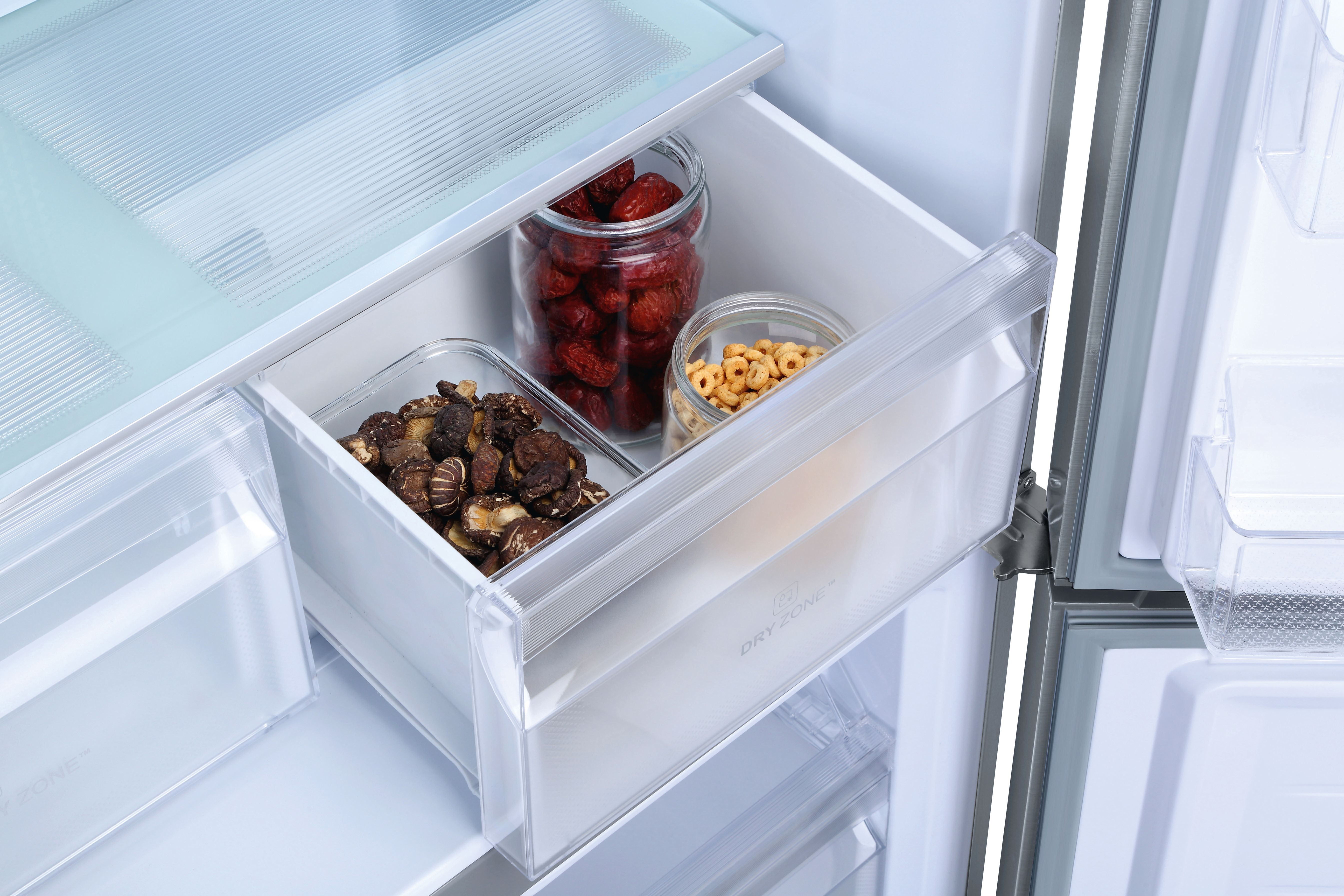 Cajón de nevera abierto con frascos de dátiles rojos, cereales y setas shiitake.