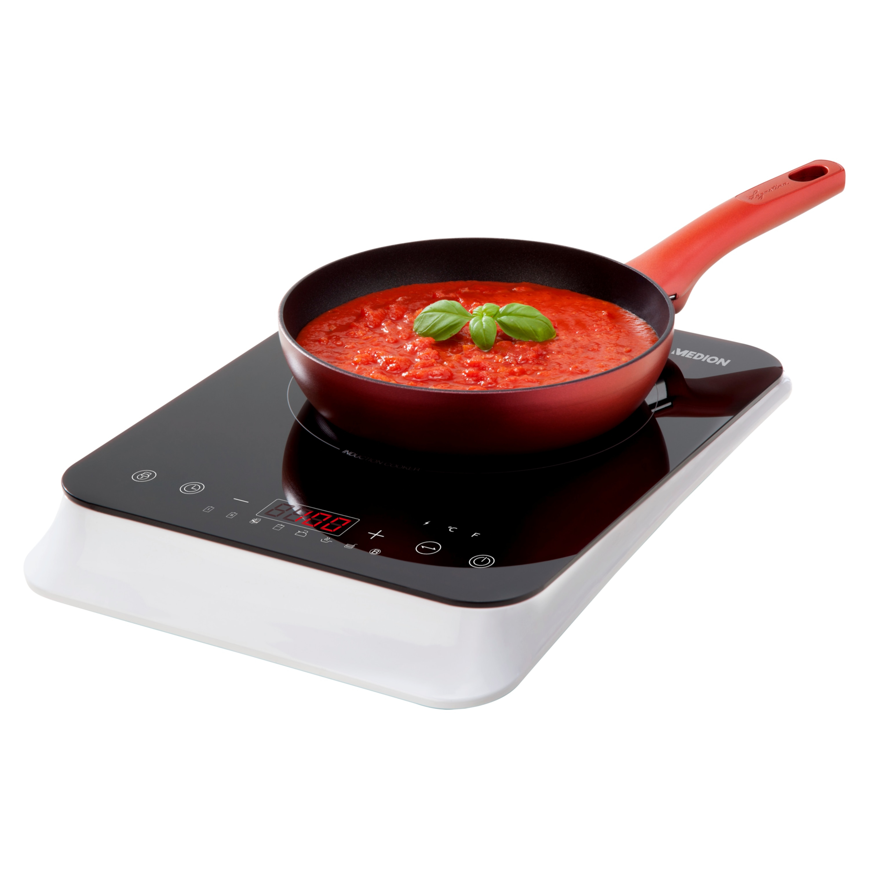 Czerwona patelnia z sosem pomidorowym i bazylią stoi na czarnej płycie indukcyjnej. Biała podstawa.