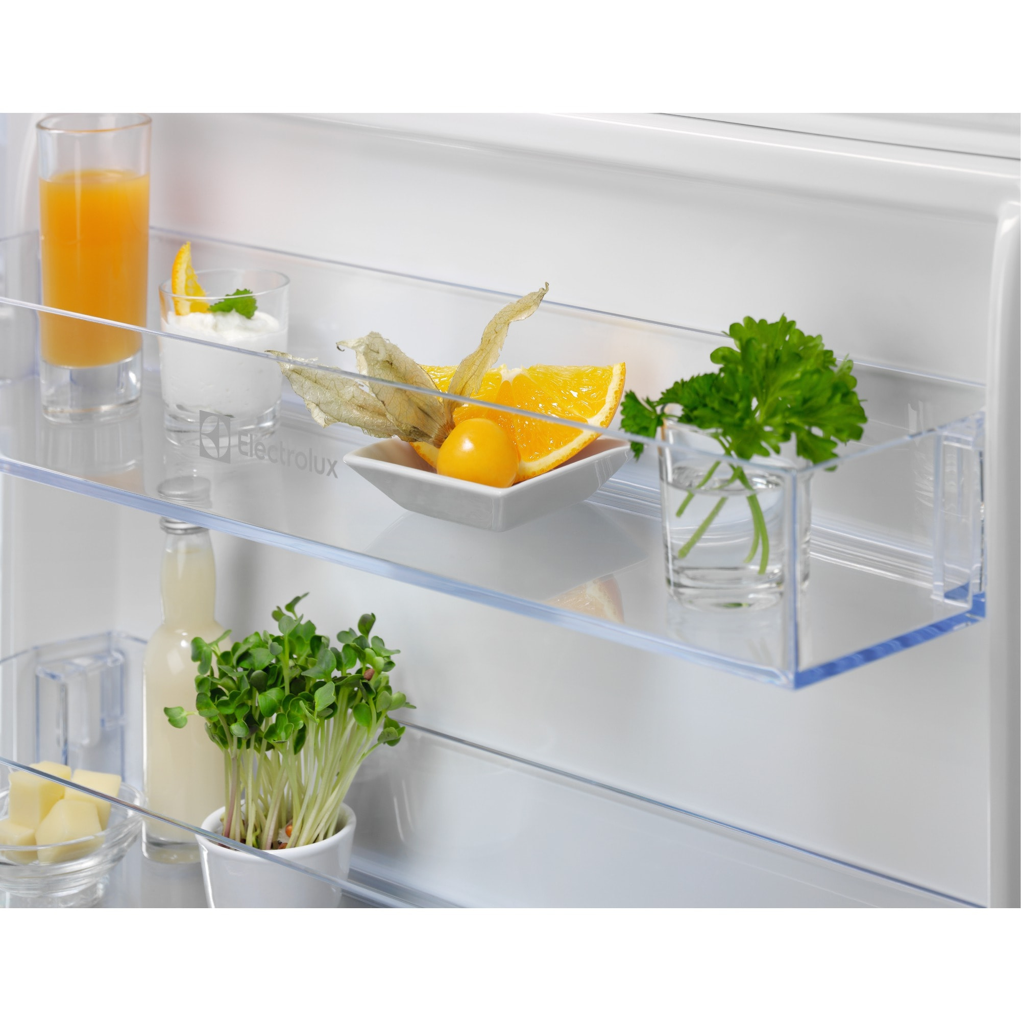 W lodówce: sok, jogurt, plasterki pomarańczy, miechunka, pietruszka, kiełki, kostki sera i butelka.