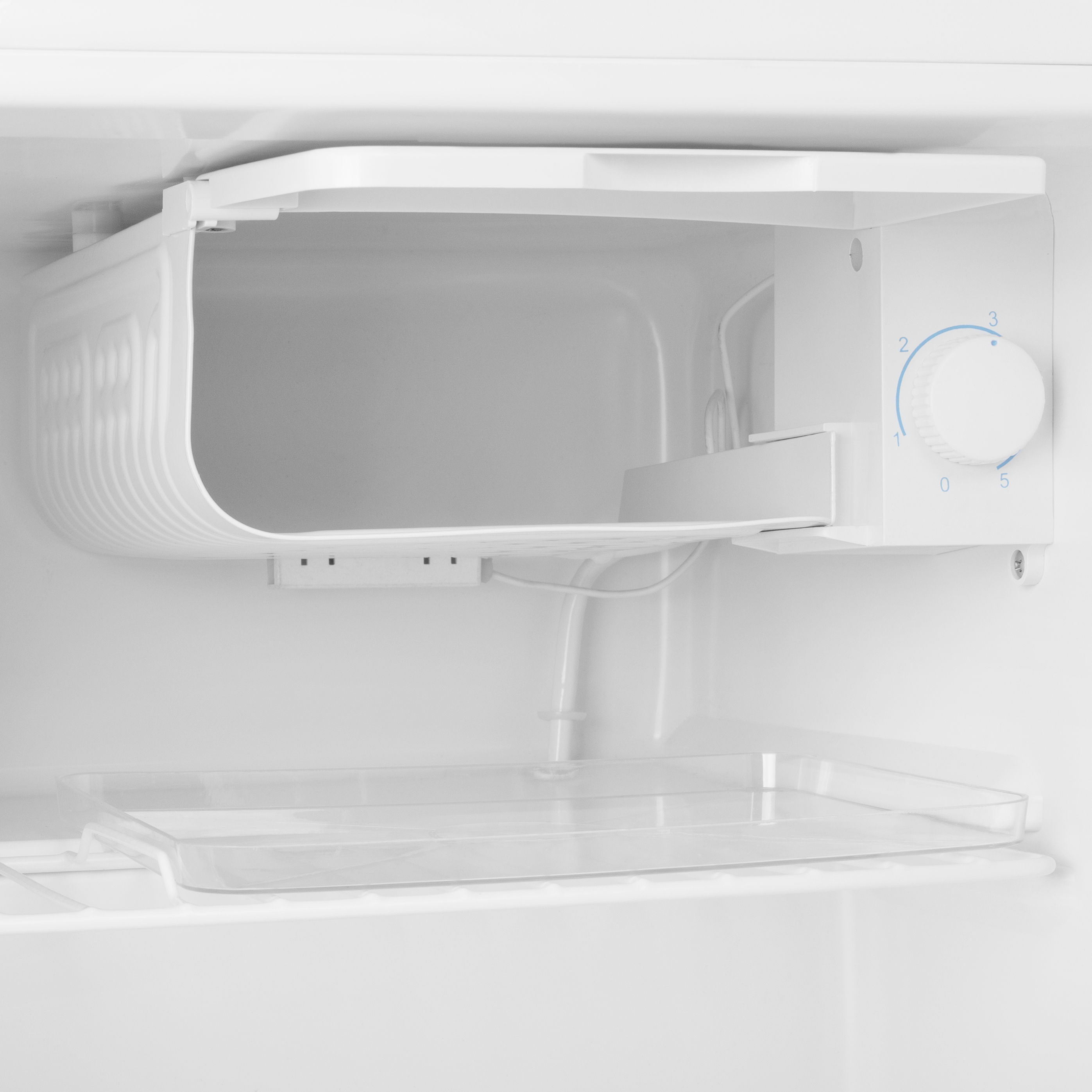 Dentro de un refrigerador blanco. Son visibles un dial de control y un estante.