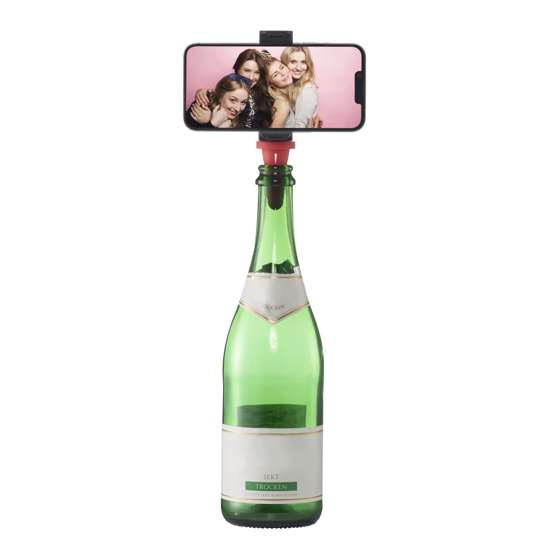 Ein Smartphone zeigt ein Foto von vier Frauen. Das Telefon ist auf einem roten Gerät montiert, das sich auf einer grünen Sektflasche befindet.
