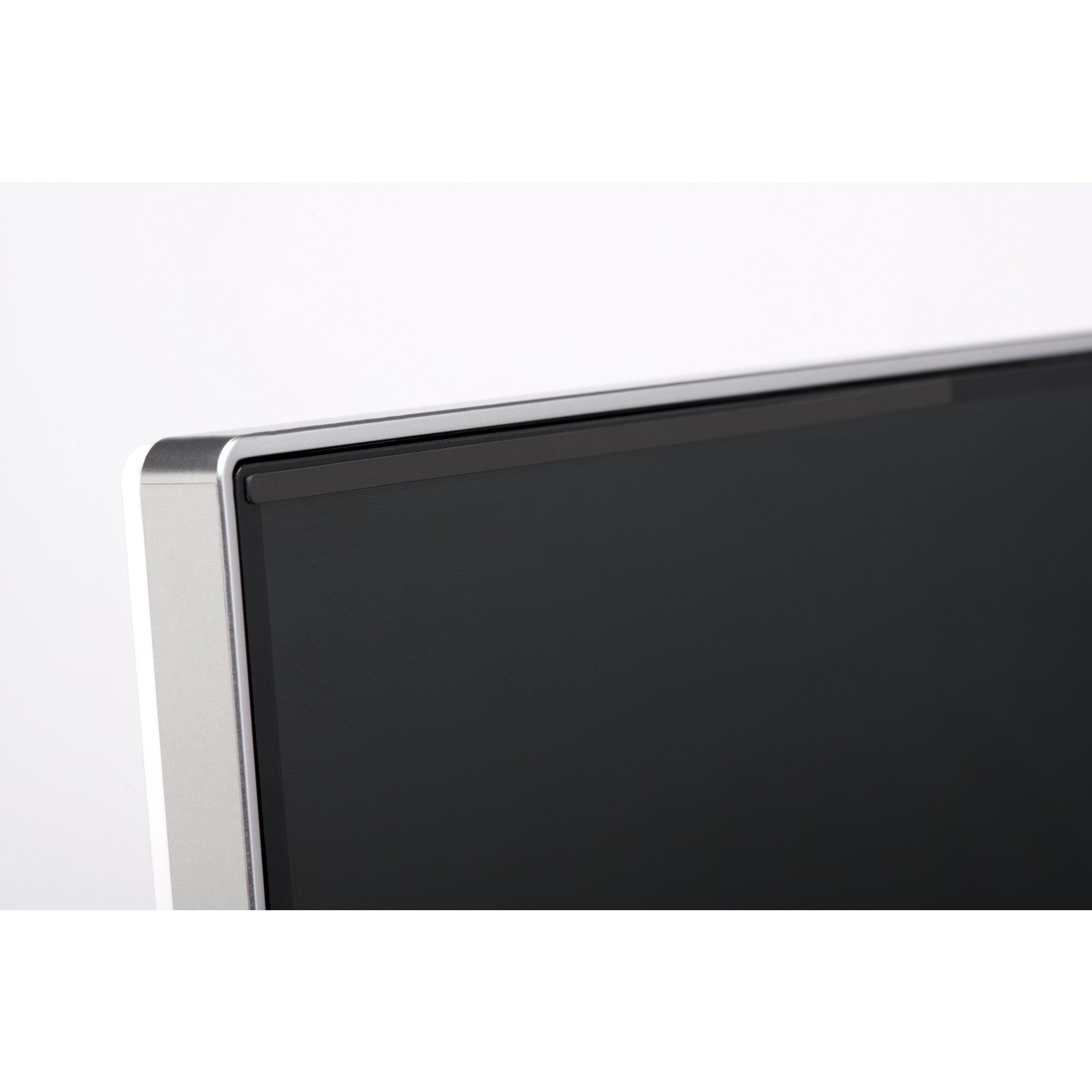 Primer plano de la esquina de un monitor. Marco plateado rodea una pantalla negra, sobre fondo blanco.
