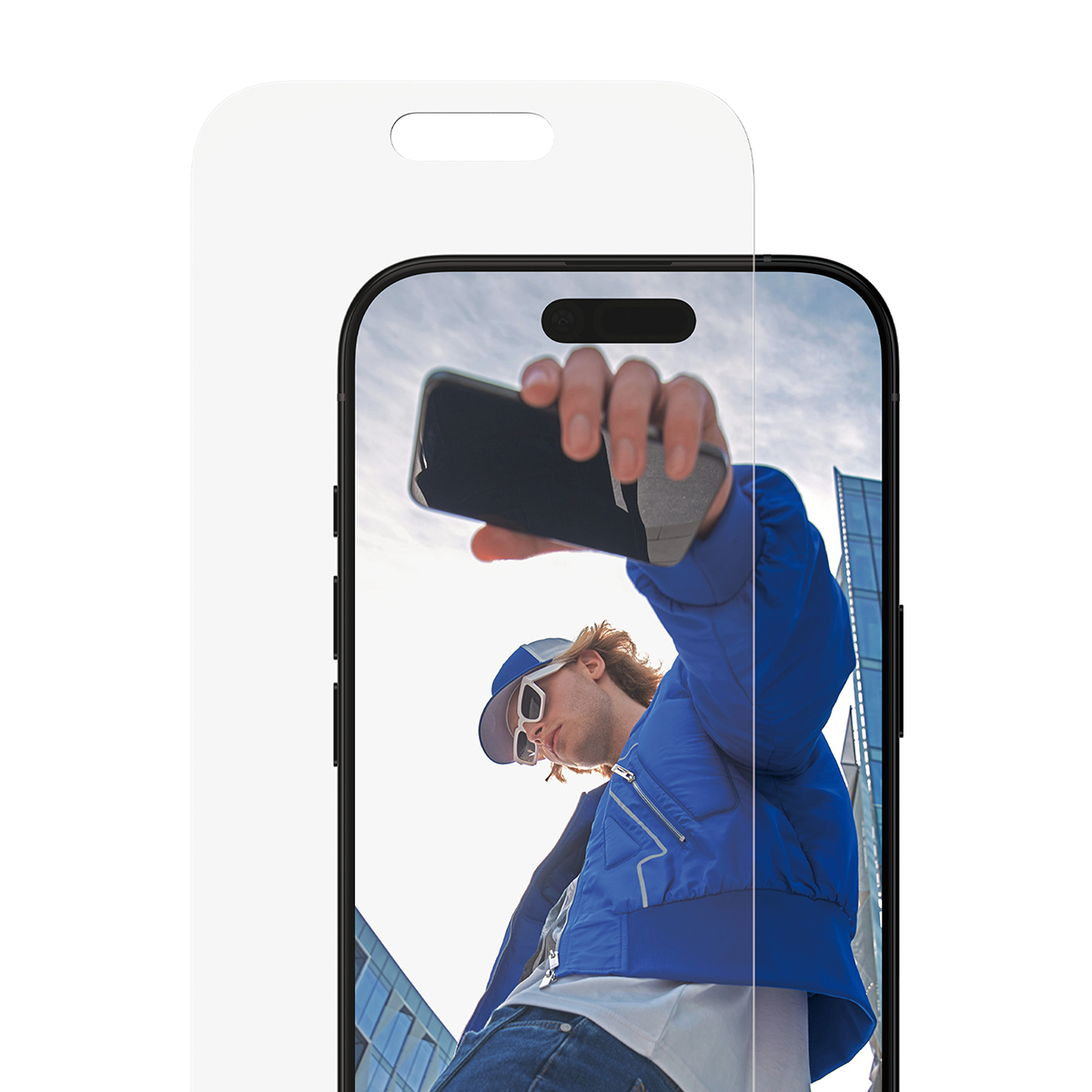 Een man in een blauwe jas maakt een selfie met een telefoon. De achtergrond toont een gebouw en de lucht.