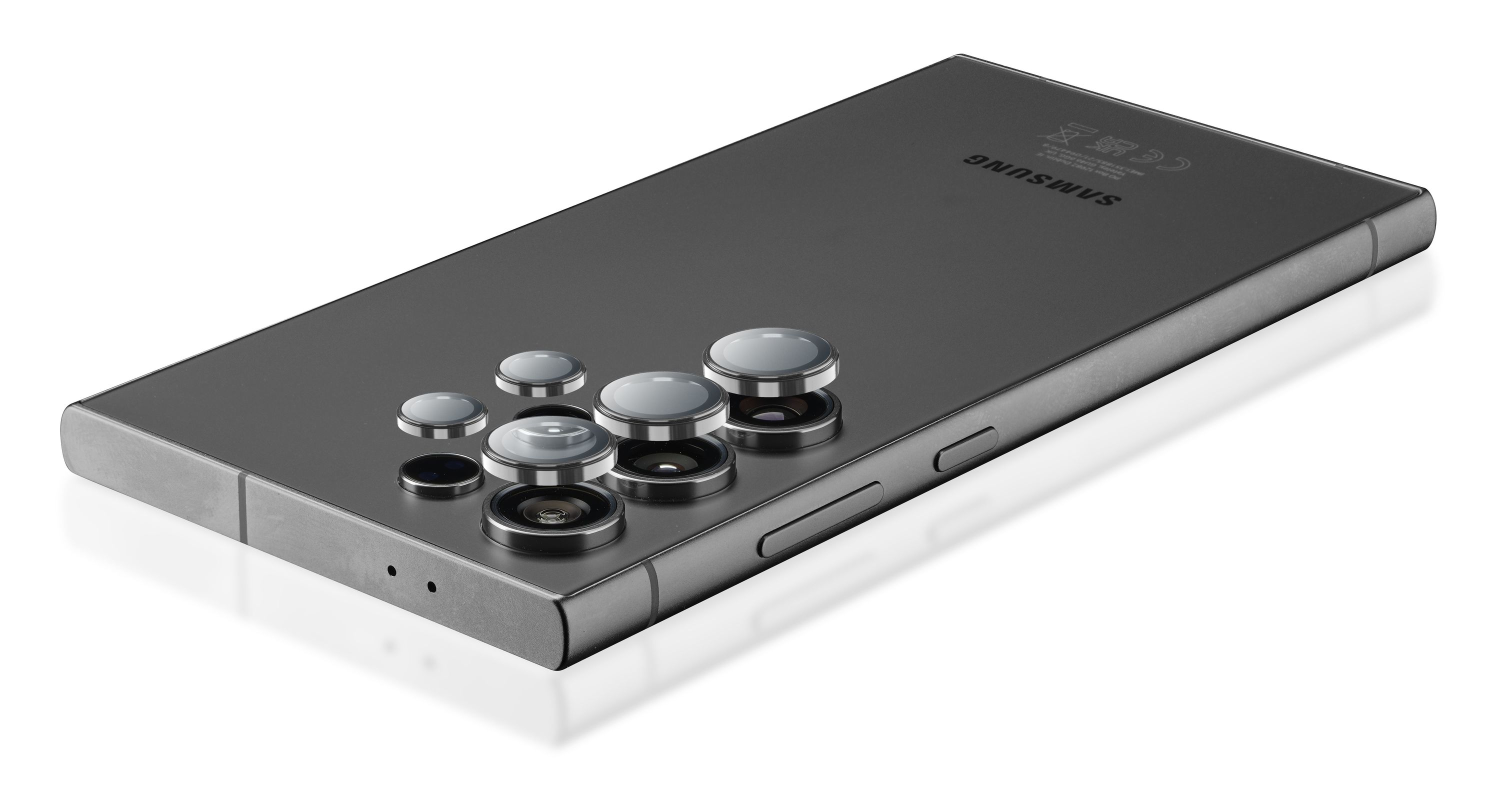 Wyświetlany jest ciemnoszary smartfon z wieloma obiektywami aparatu. Widoczne jest logo Samsung. Telefon leży na białej powierzchni.