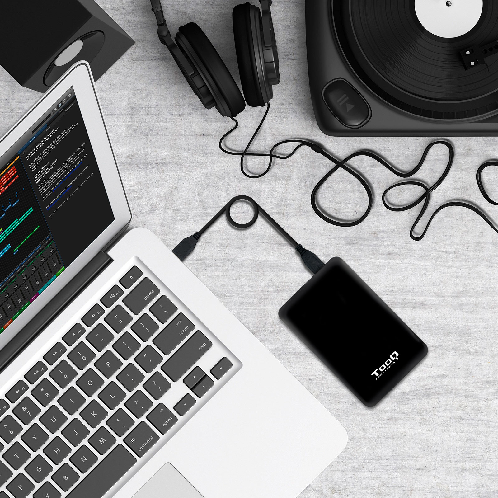 Un portátil, auriculares, un tocadiscos y un disco duro externo están sobre una superficie texturizada.
