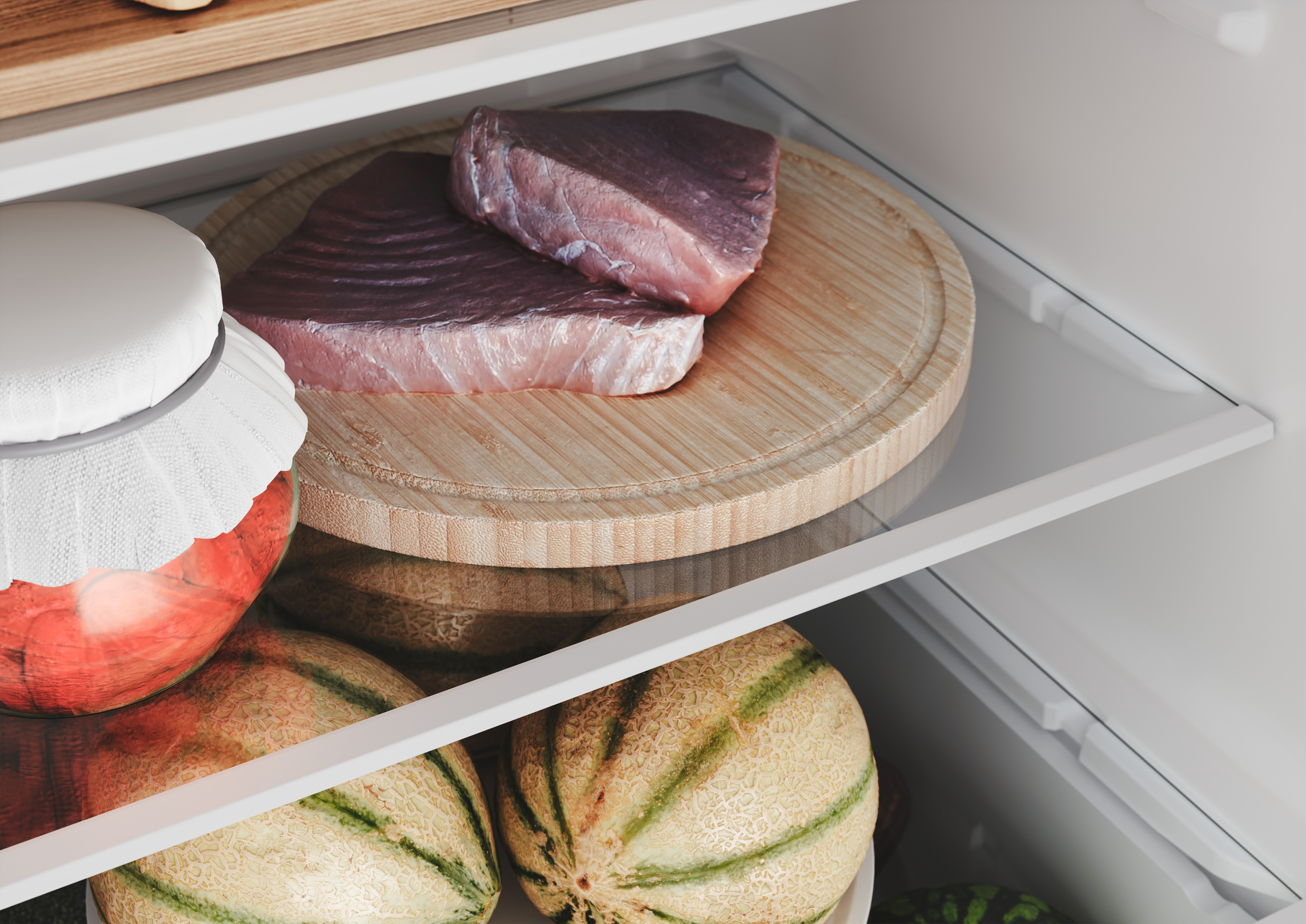 Wnętrze lodówki z tuńczykiem na desce, słoikiem i melonami.