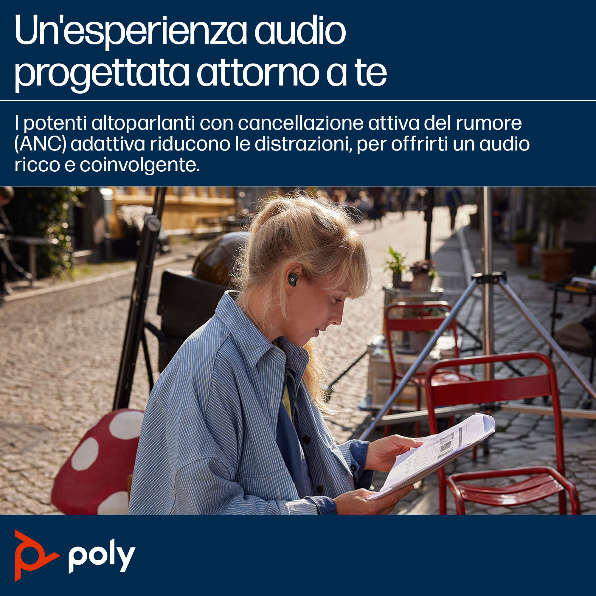 Una donna con auricolari legge uno script all'aperto. Sedie rosse, un fungo e attrezzature sullo sfondo.