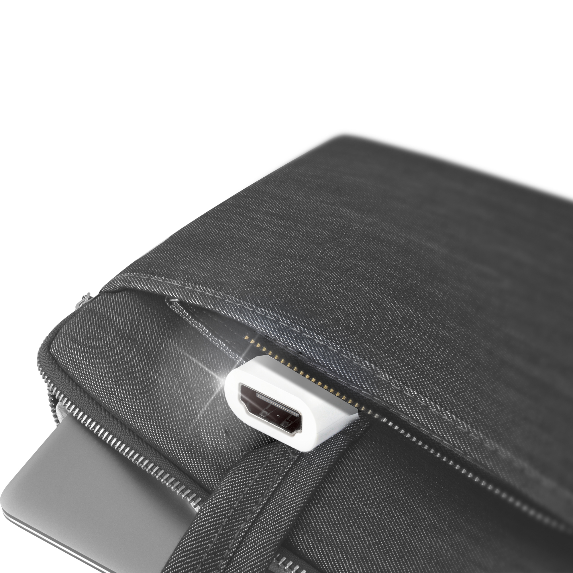 Un conector HDMI blanco sobresale de una funda para portátil de mezclilla negra, parcialmente cerrada. Una laptop es visible.