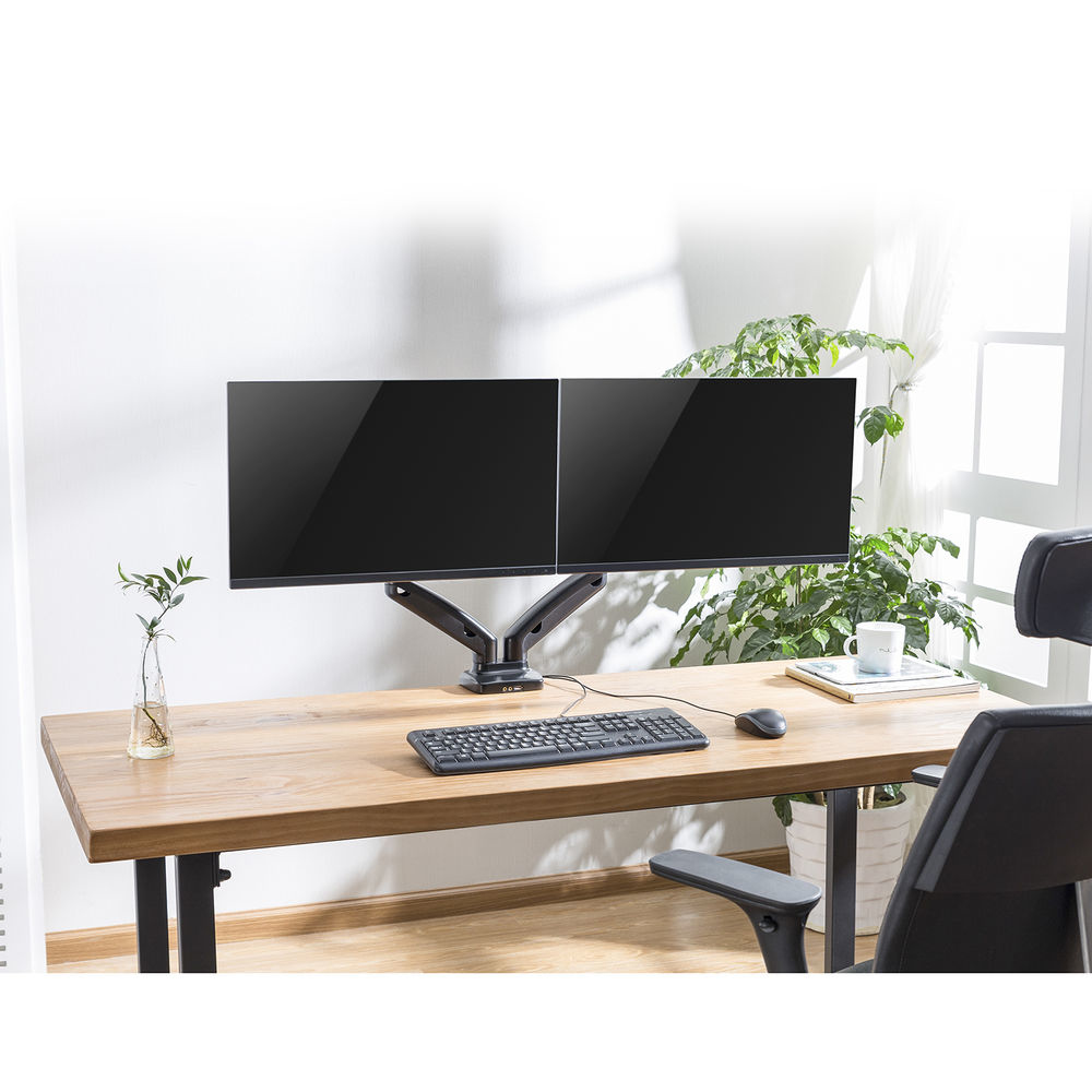 Bureau-opstelling met twee monitoren, toetsenbord, muis en stoel. Een plant en een kopje op het bureau. Witte muur en raam op de achtergrond.