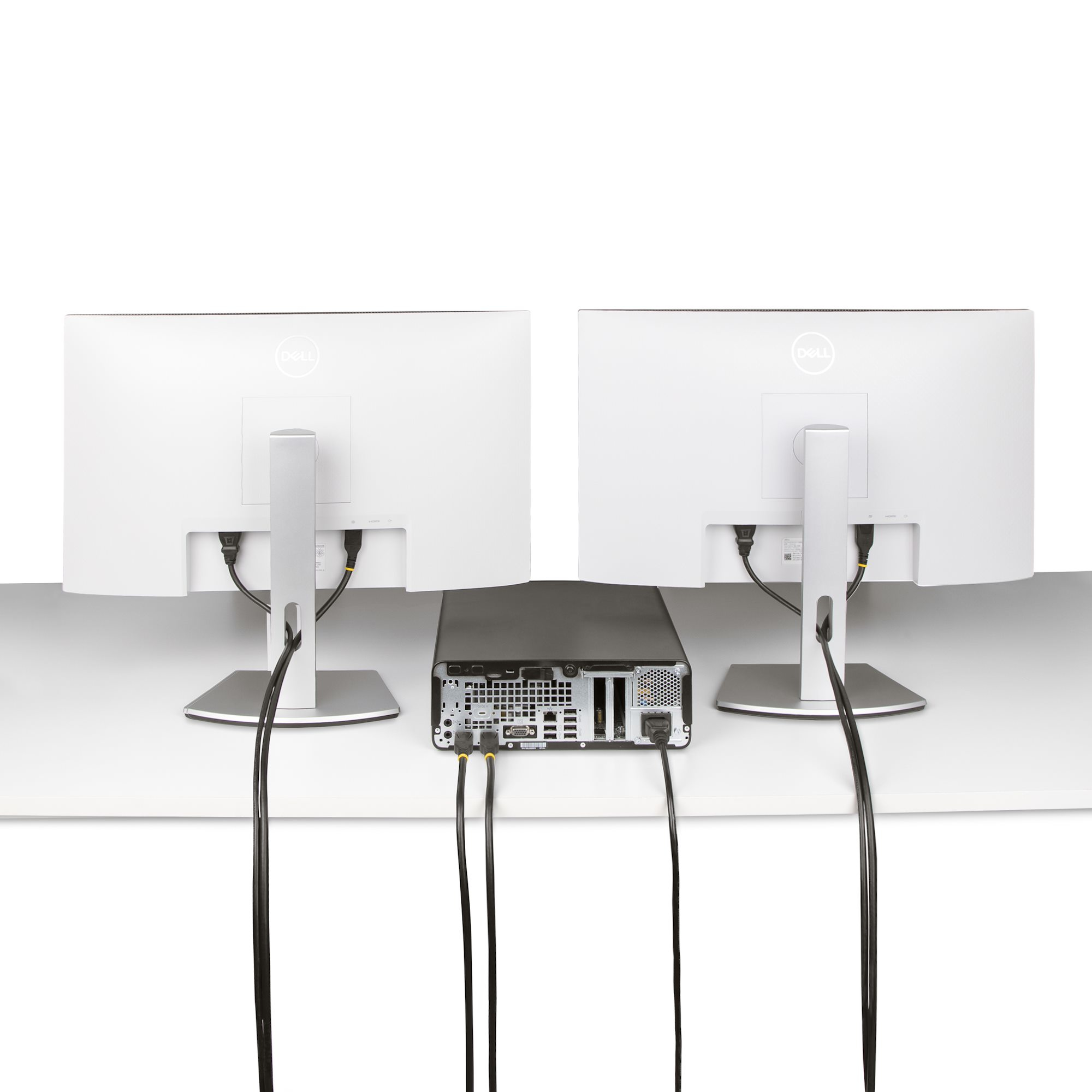 Zwei Dell-Monitore stehen auf einem weißen Schreibtisch mit einem schwarzen Computer dazwischen. Kabel verbinden die Monitore mit dem Computer.