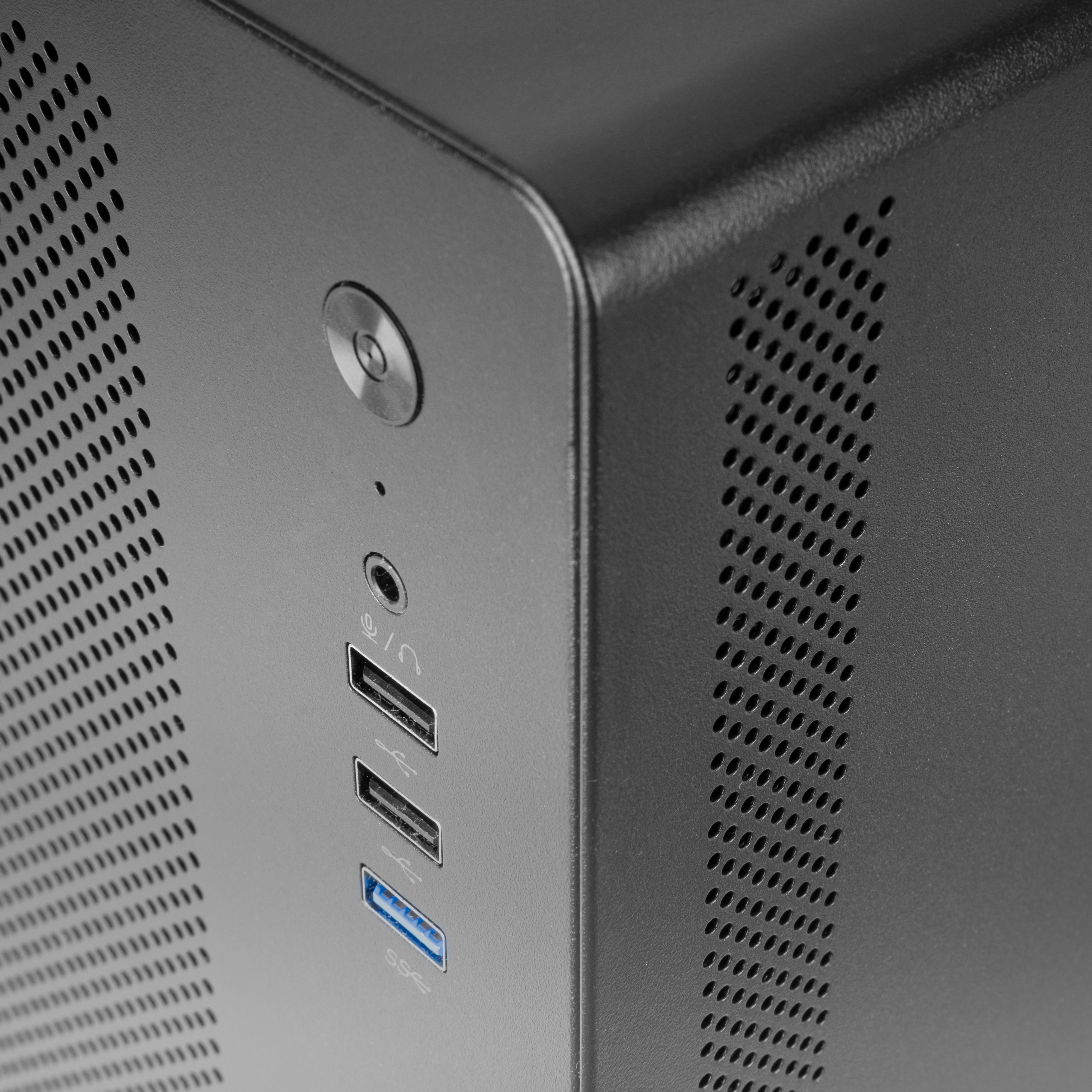 Primo piano di un case di computer nero. Ha un pulsante di accensione, porte e fori di ventilazione. La superficie è strutturata.