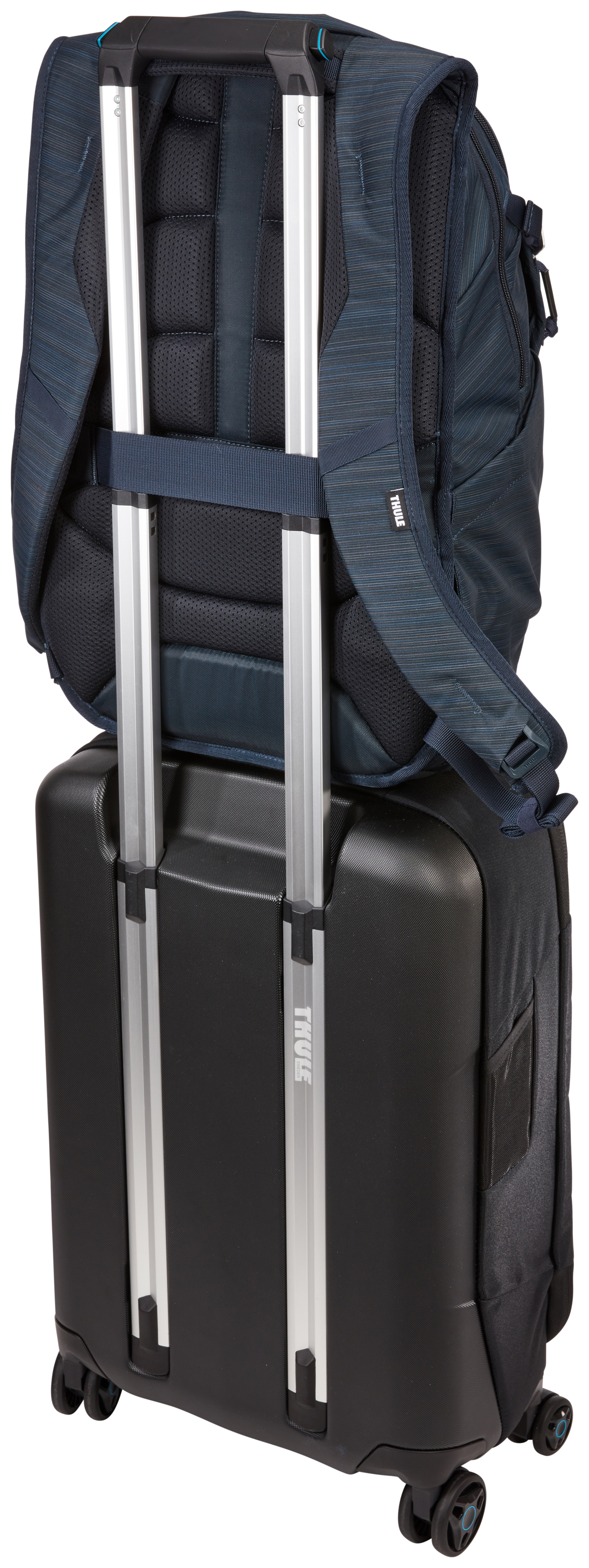 Ein marineblauer Rucksack liegt auf einem schwarzen Koffer. Silberne Griffe ragen aus dem Koffer. Das Thule-Logo ist sichtbar.