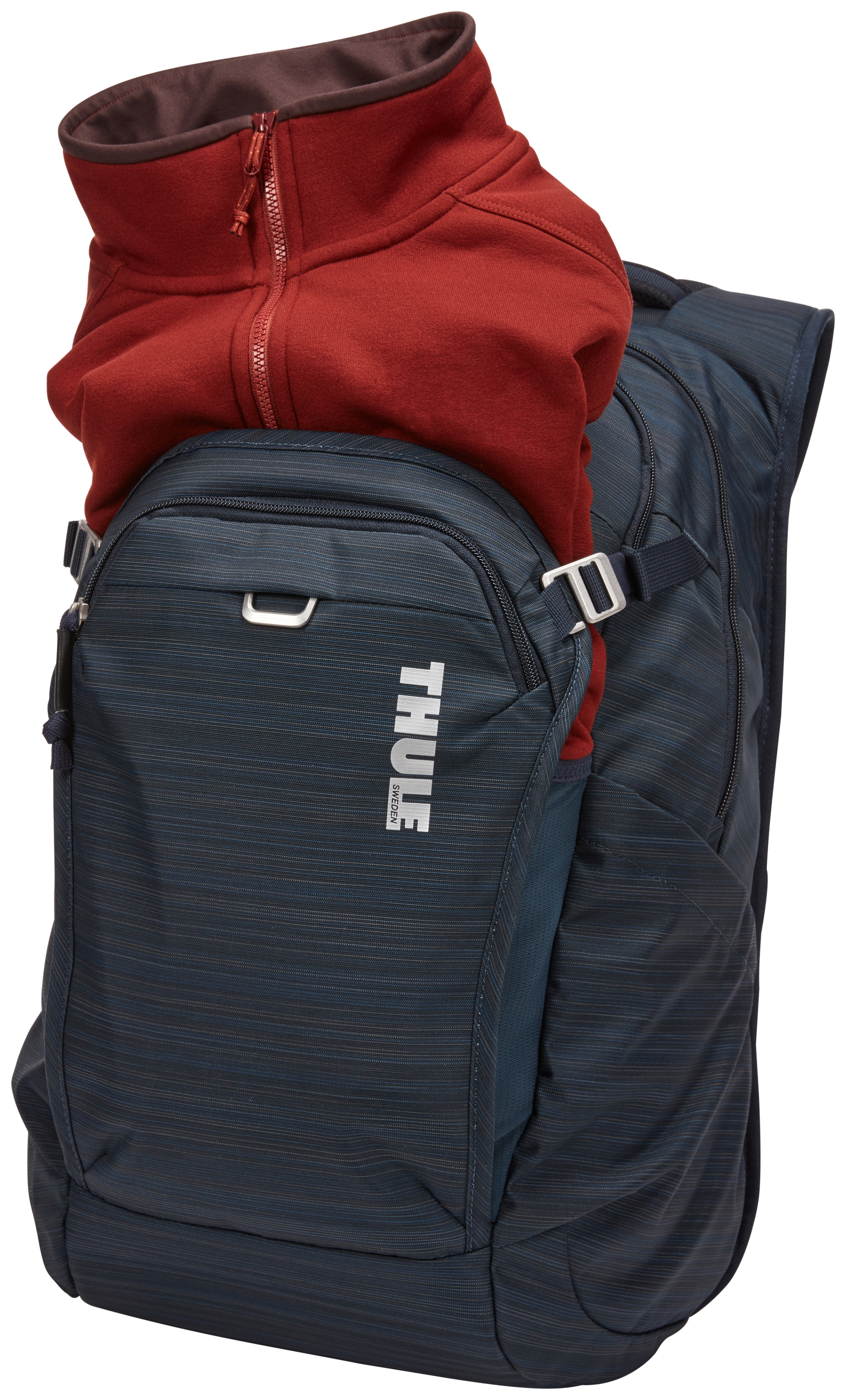 Ein dunkelblauer Rucksack mit einer roten Jacke oben drauf. Der Rucksack hat den Markennamen 'THULE'. Die Jacke ist zugeknöpft.