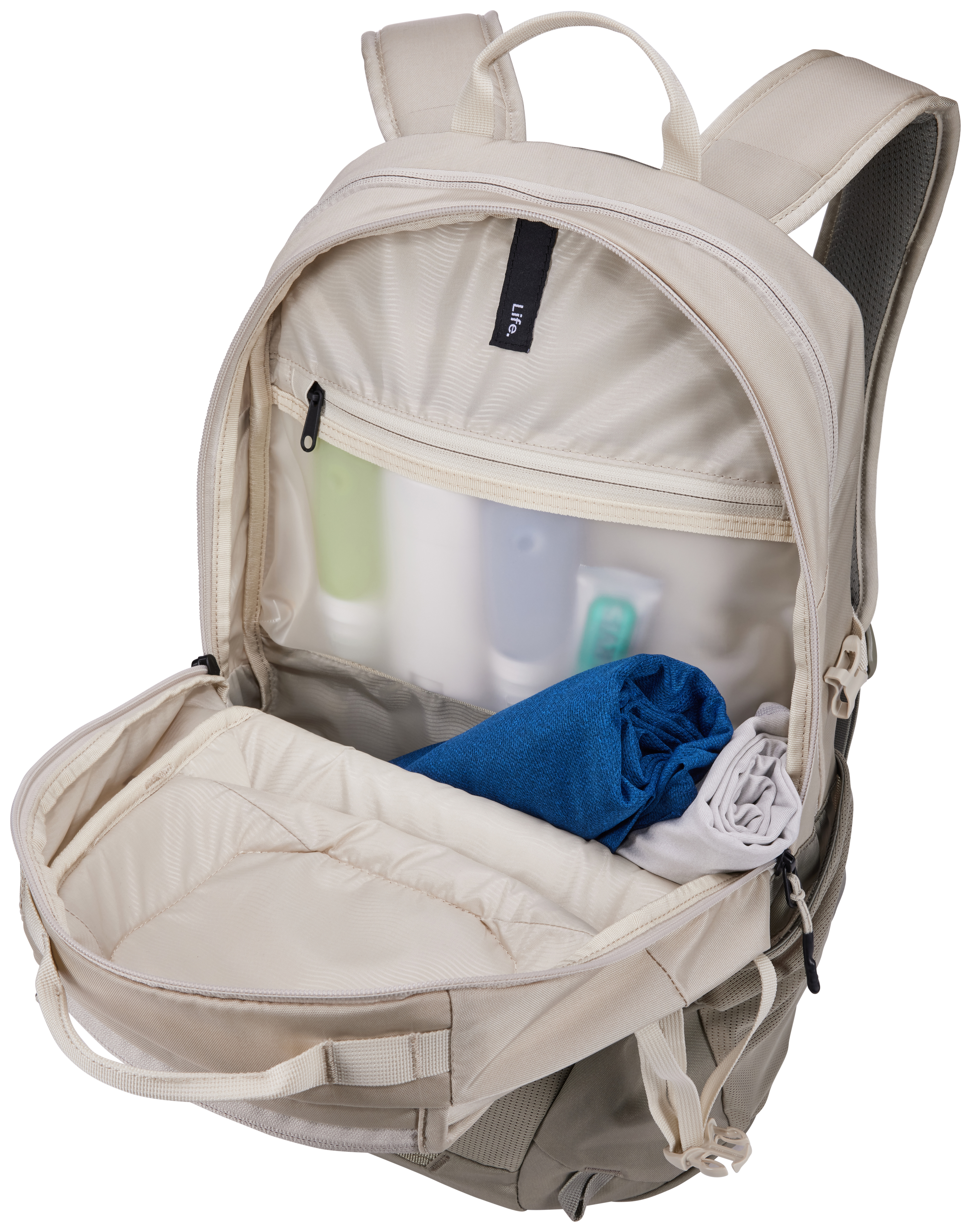 Offener beiger Rucksack mit Inhalt: blaues Handtuch, graues Handtuch und Toilettenartikel.