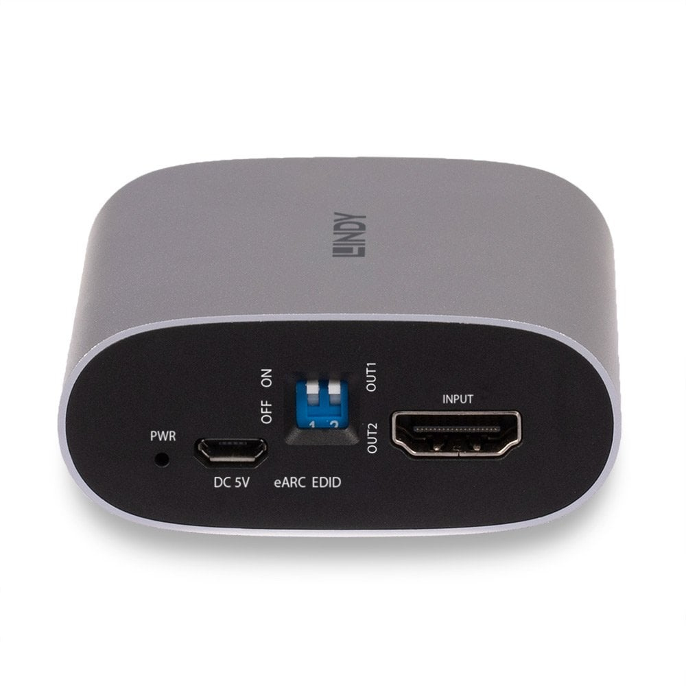 Ein graues Lindy HDMI-Gerät. Es hat Ein-/Ausgänge, einen Stromeingang und einen Schalter. Das Gerät steht auf einer weißen Oberfläche.
