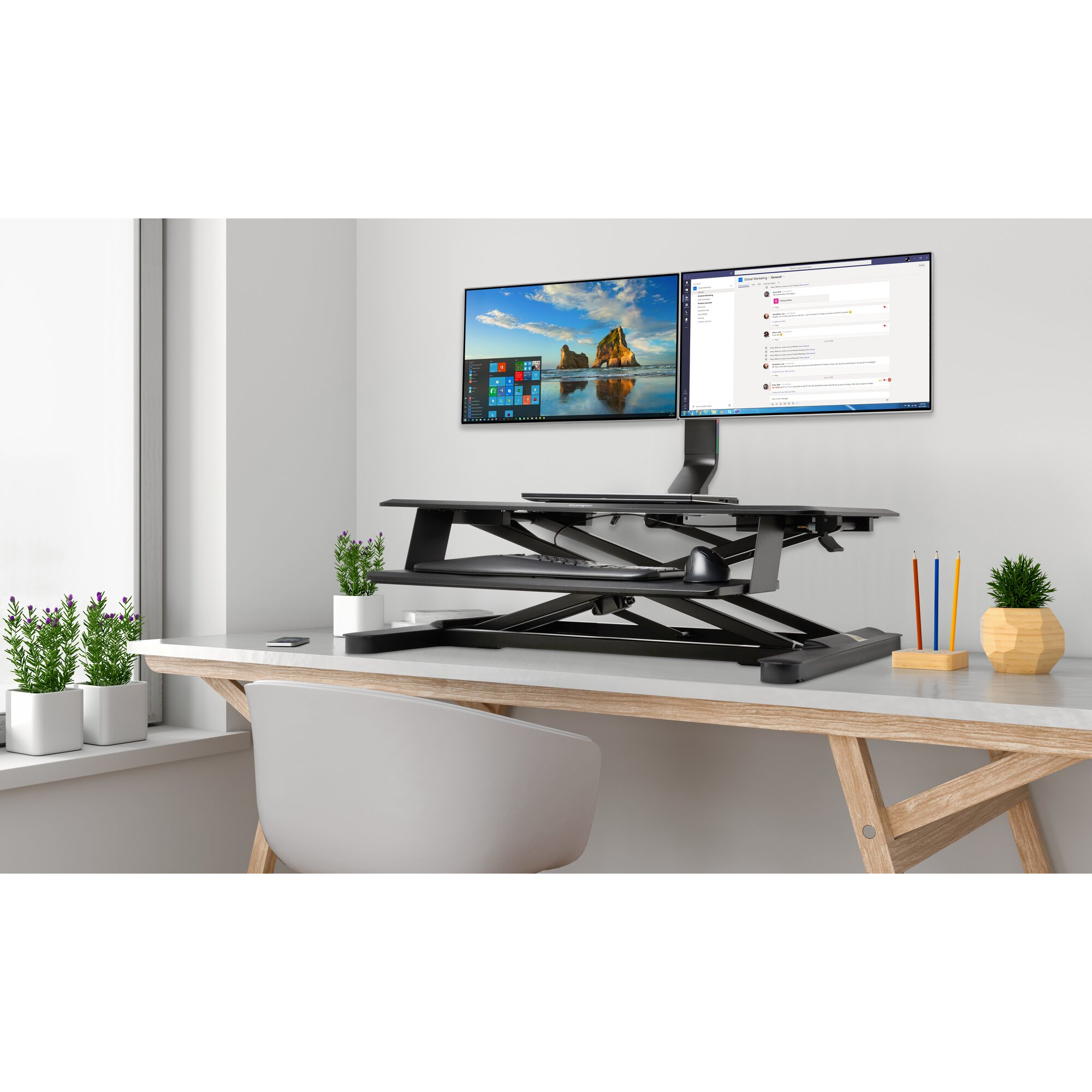 A desk setup with two monitors, keyboard, mouse, plants, and pencils. A window and a chair complete the scene.