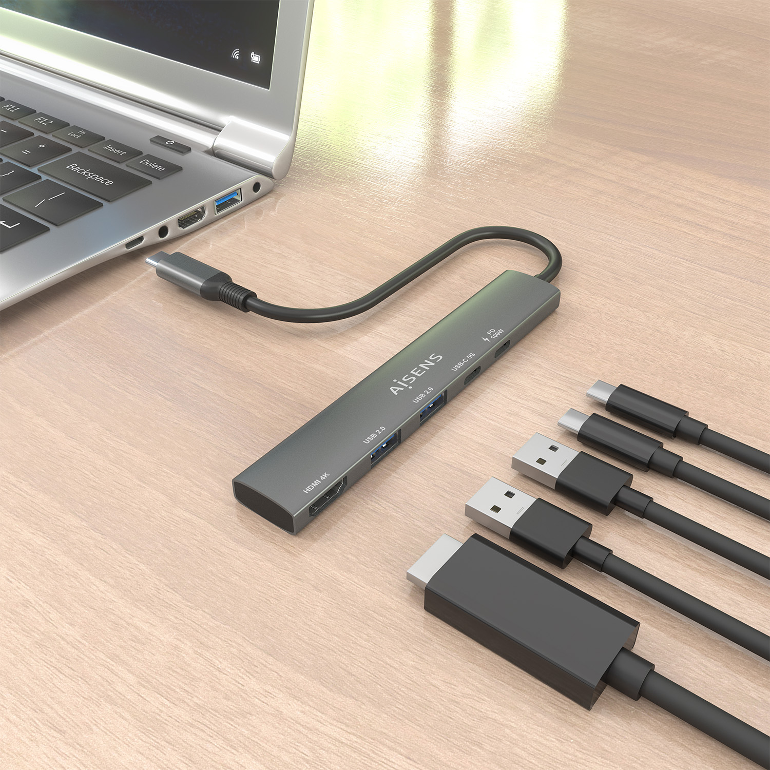 Un laptop con un hub USB grigio collegato e cavi su un tavolo di legno. L'hub ha più porte. I cavi sono neri.